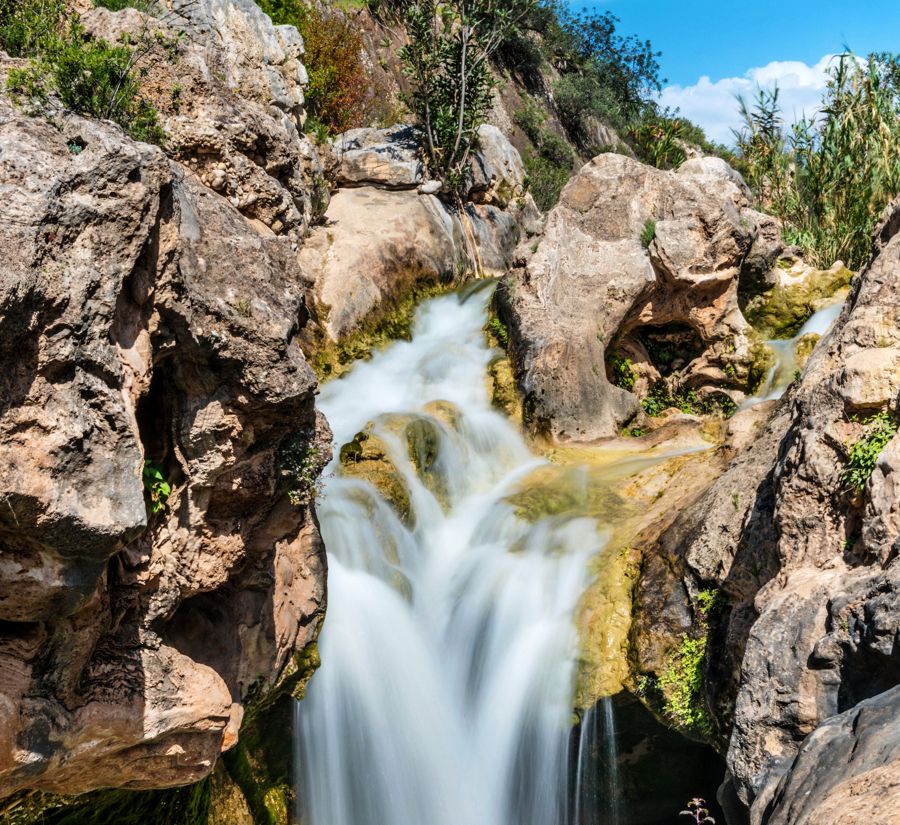 Waterfall cascading over rocks in a gorge HD Wallpaper