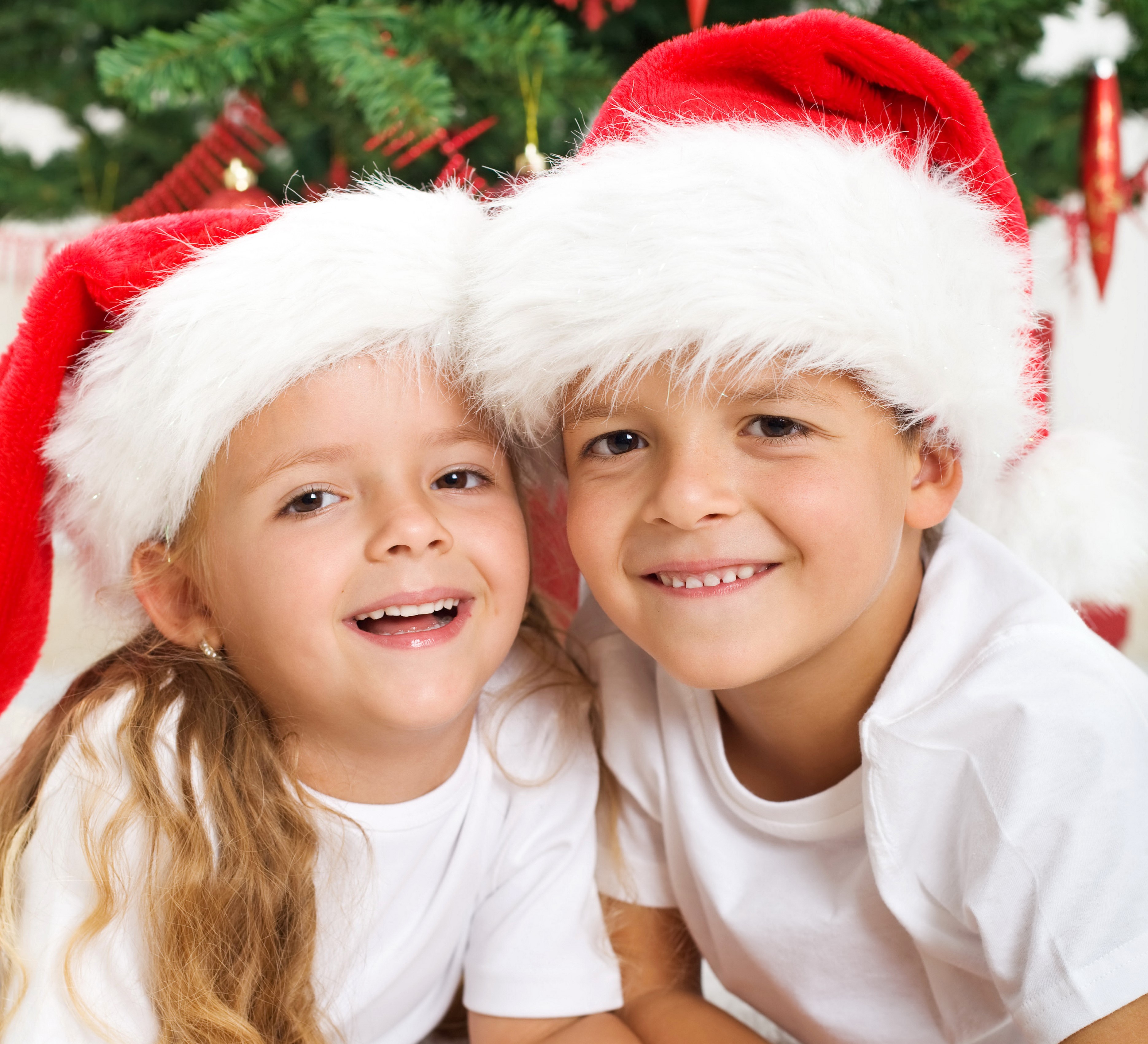Two children wearing Santa hats at Christmas HD Wallpaper