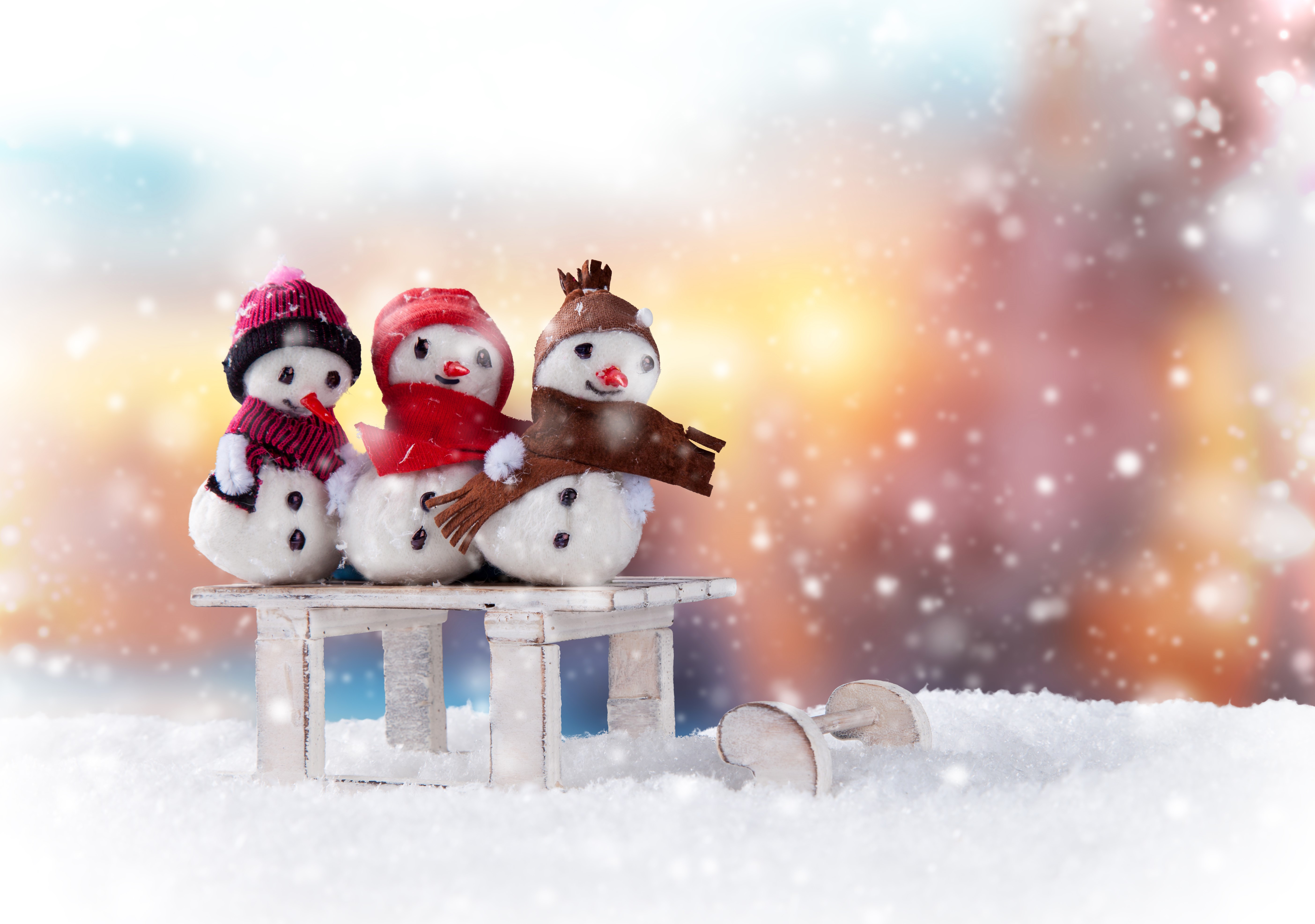 Three snowmen with winter hats and scarves on a bench HD Wallpaper