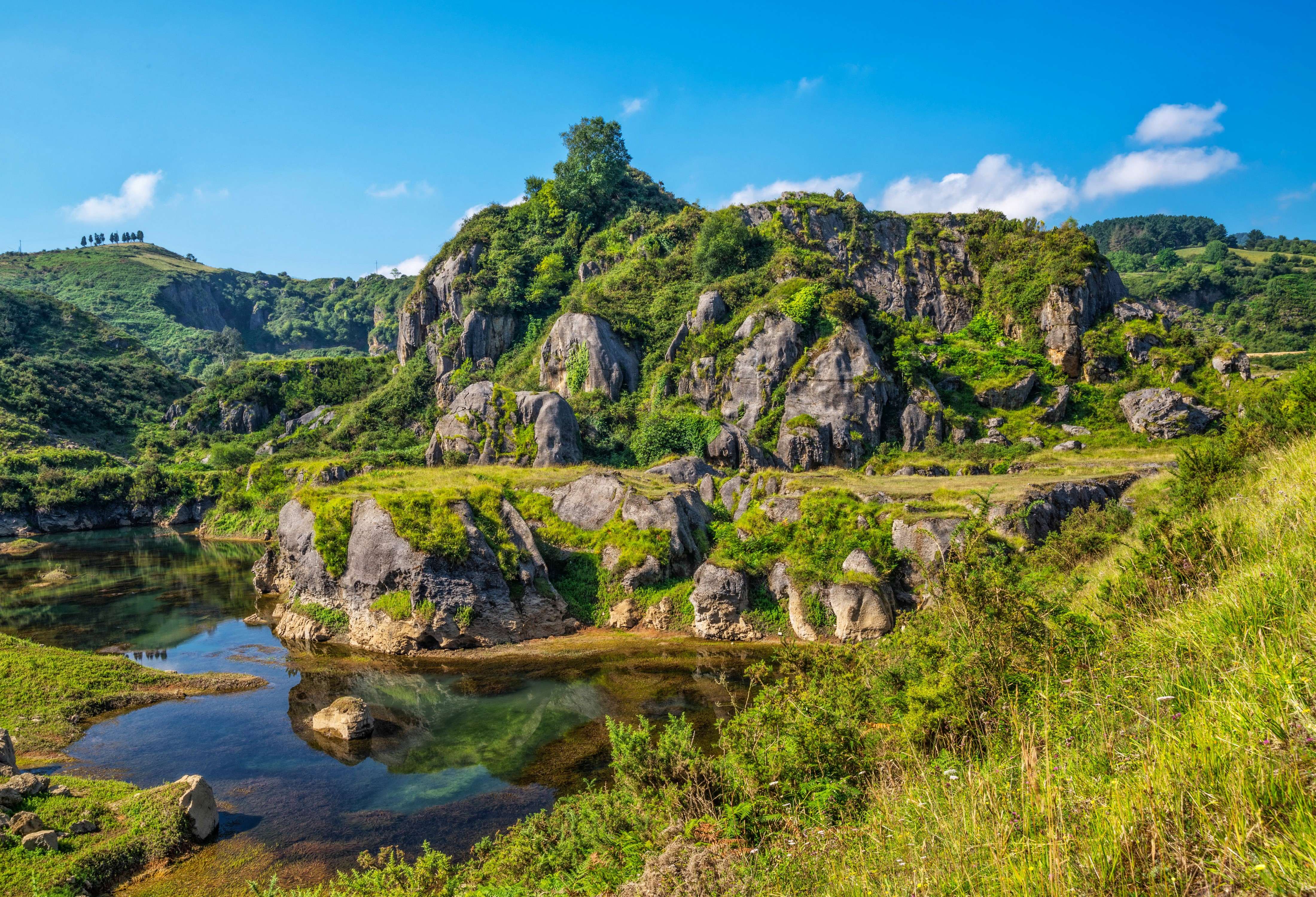 Rocky landscape with a lake and green hills HD Wallpaper