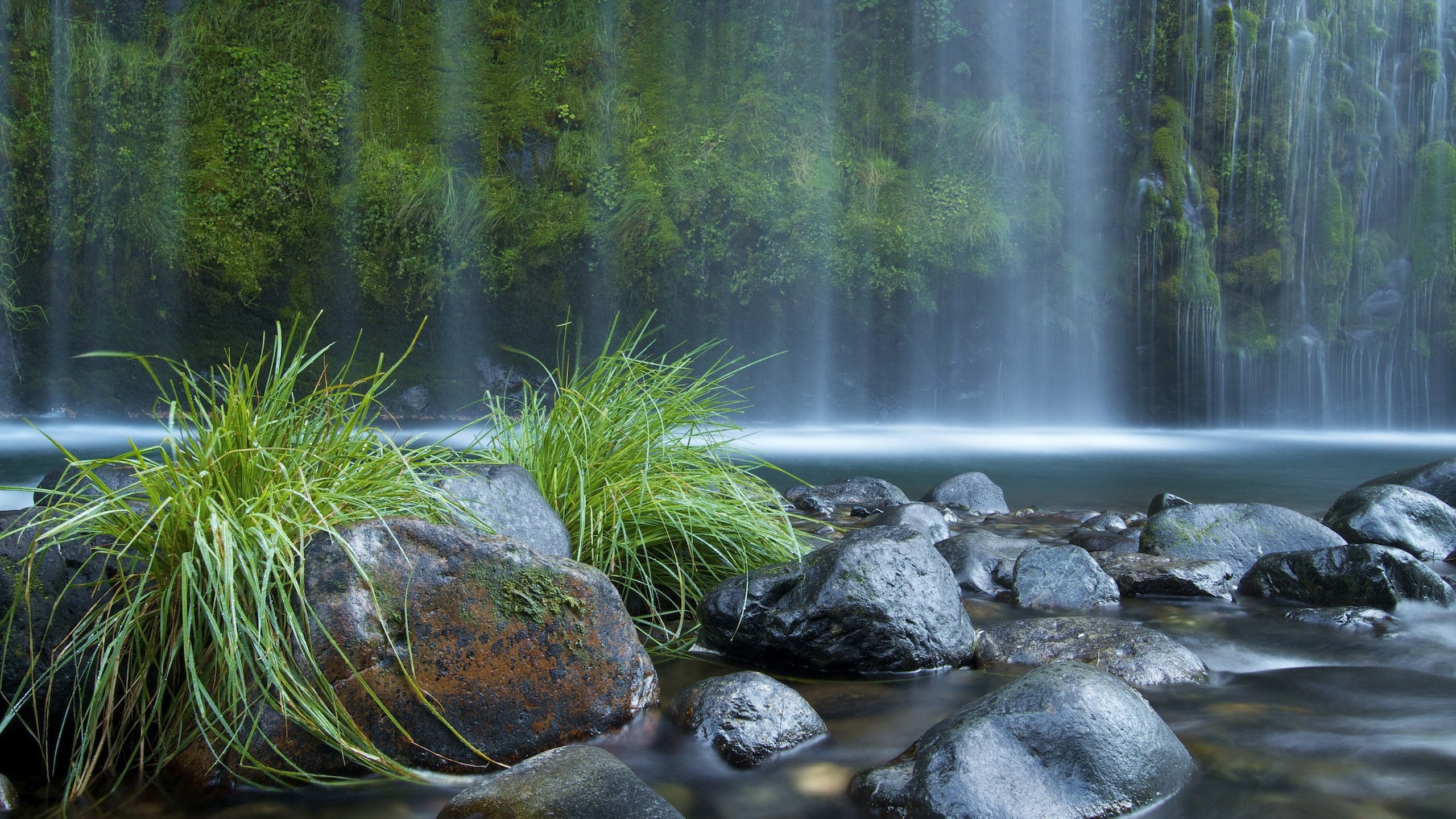 Waterfall cascading over mossy rocks into a stream HD Wallpaper