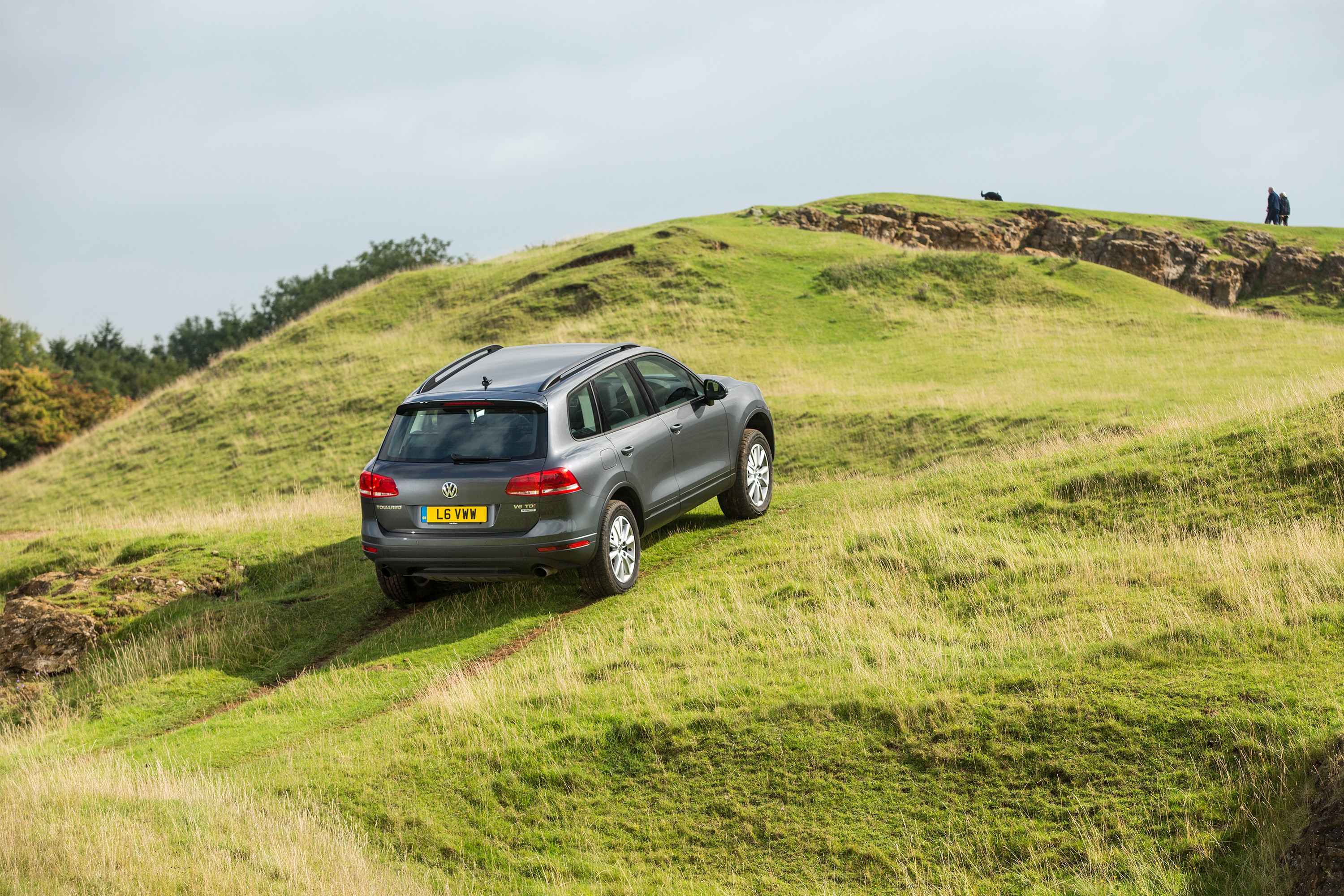 Grey Volkswagen Touareg driving on grassy hills HD Wallpaper
