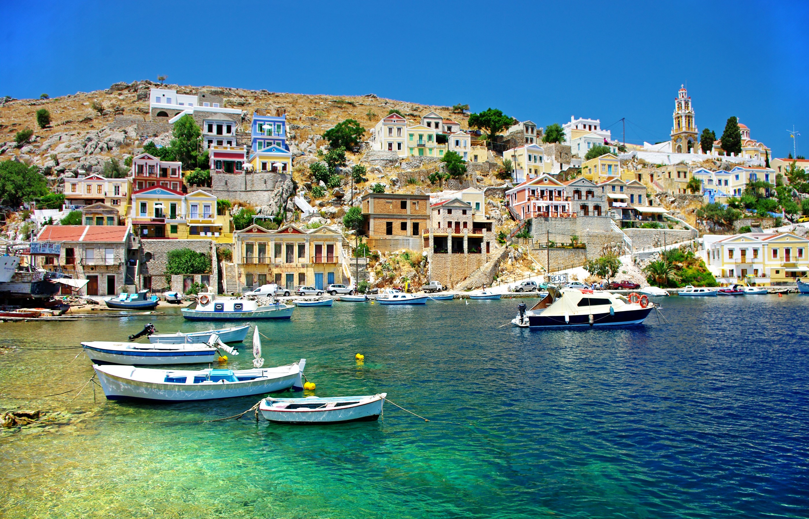 Colorful houses on a hill overlooking a harbor in Greece HD Wallpaper