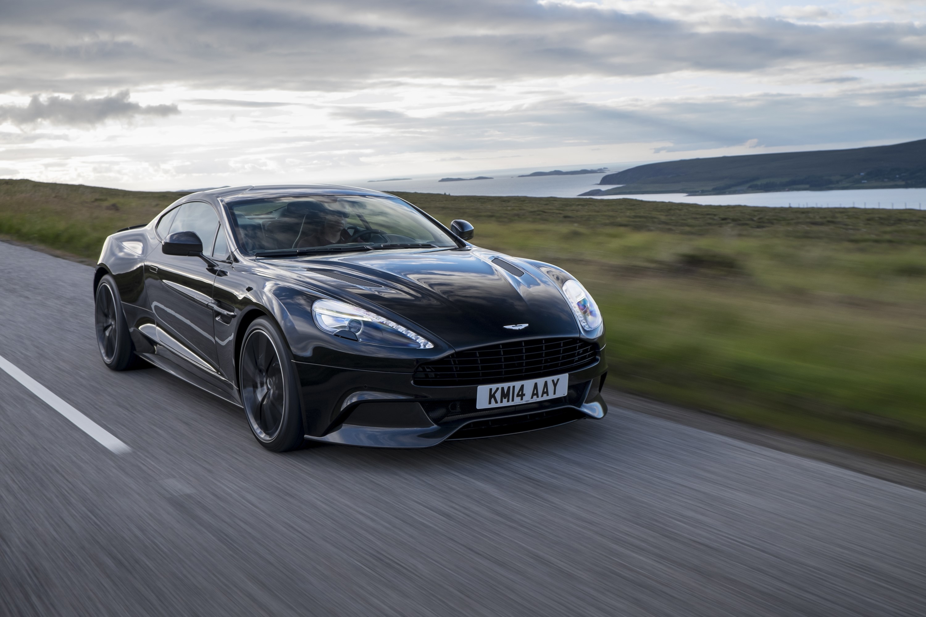 Black Aston Martin Vanquish driving on a road HD Wallpaper