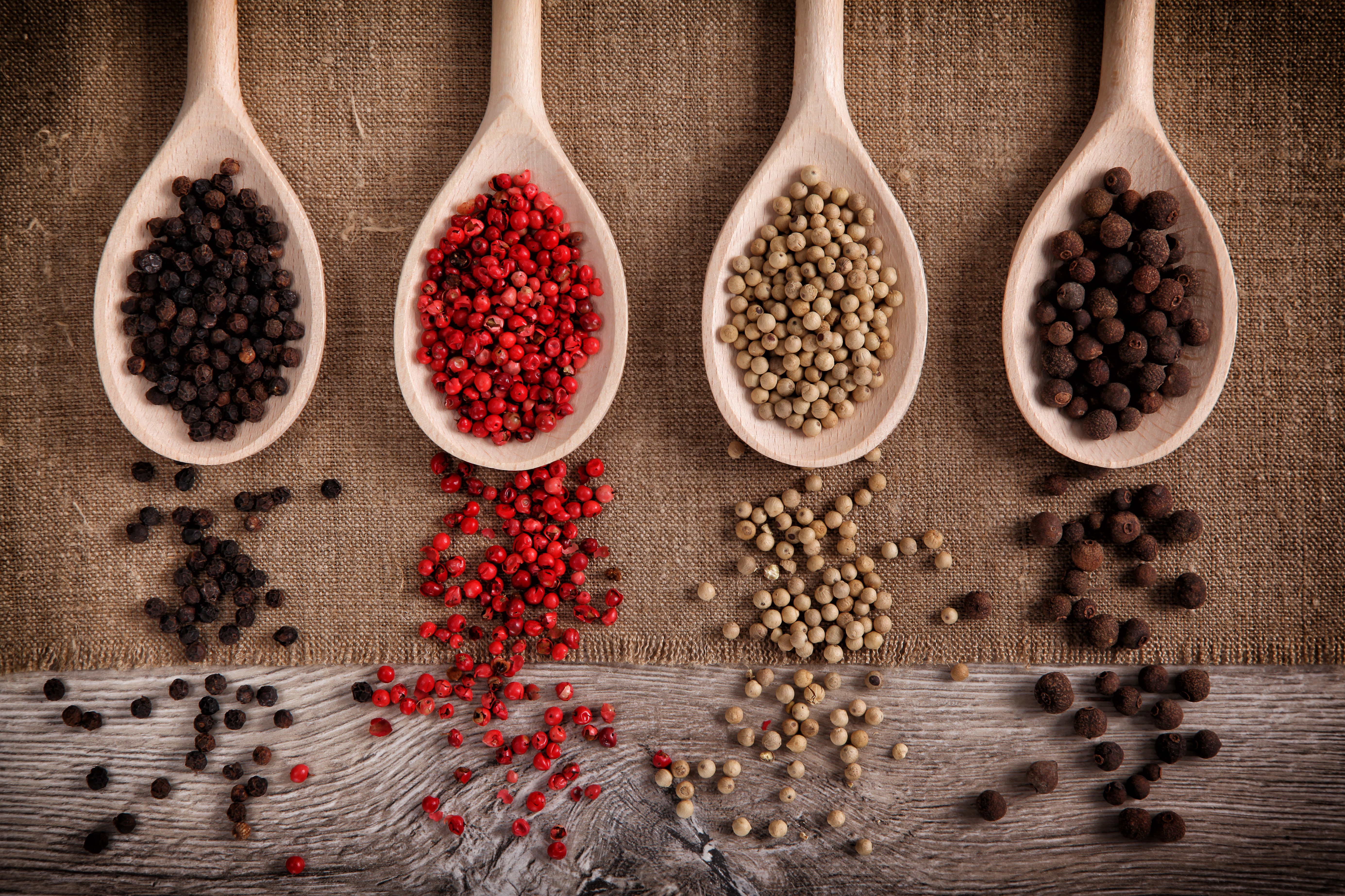 Four wooden spoons filled with different peppercorns HD Wallpaper