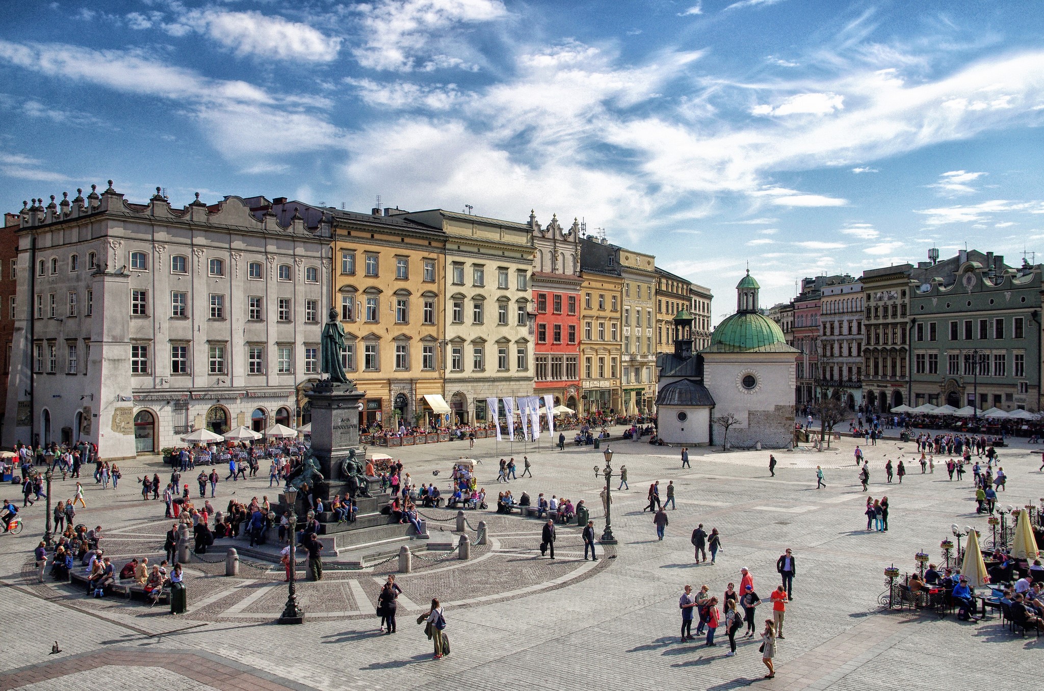 People in Krakow Town Square with colorful buildings HD Wallpaper