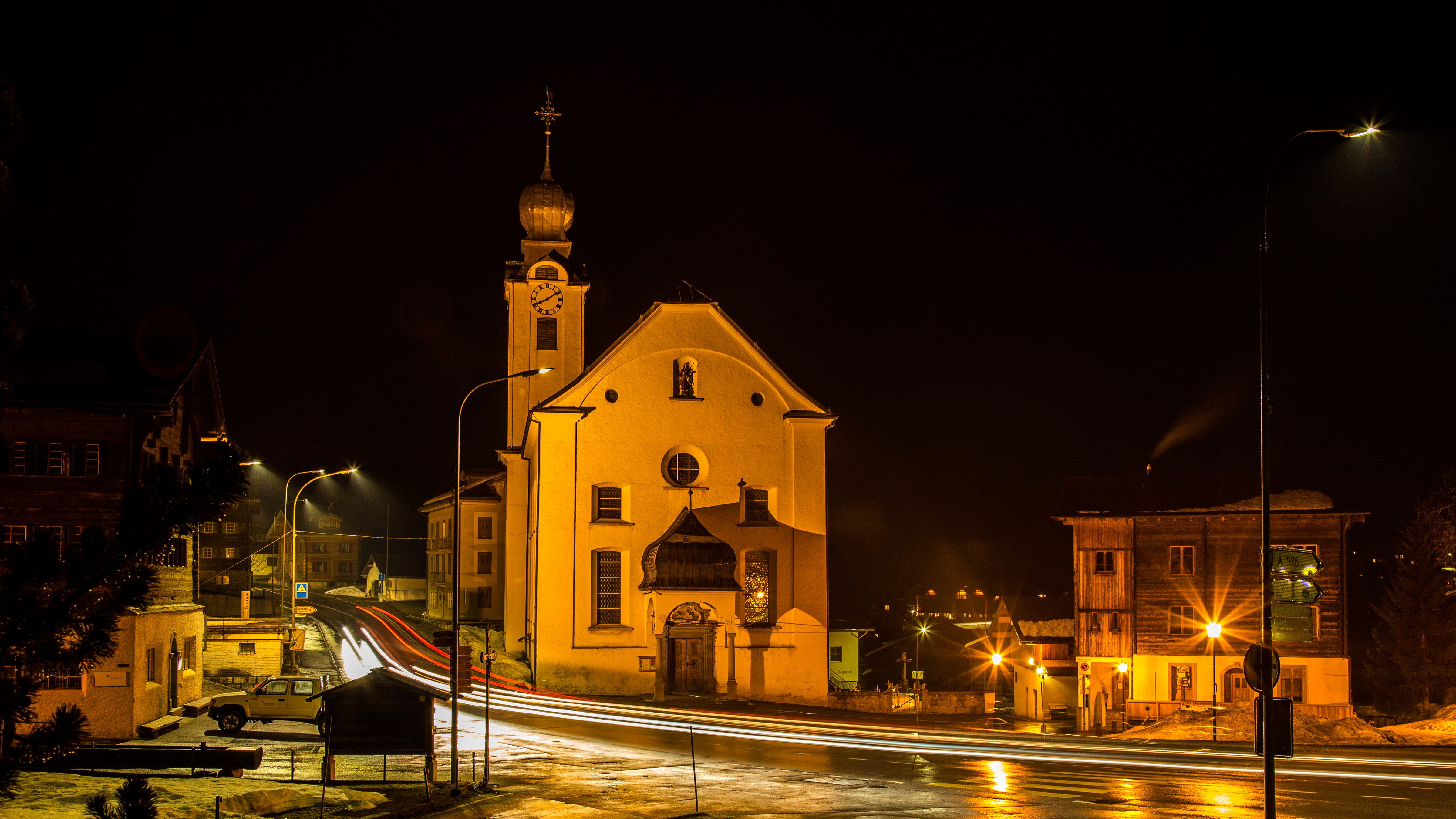 Night view of Reckingen, Switzerland with illuminated church and street lights HD Wallpaper