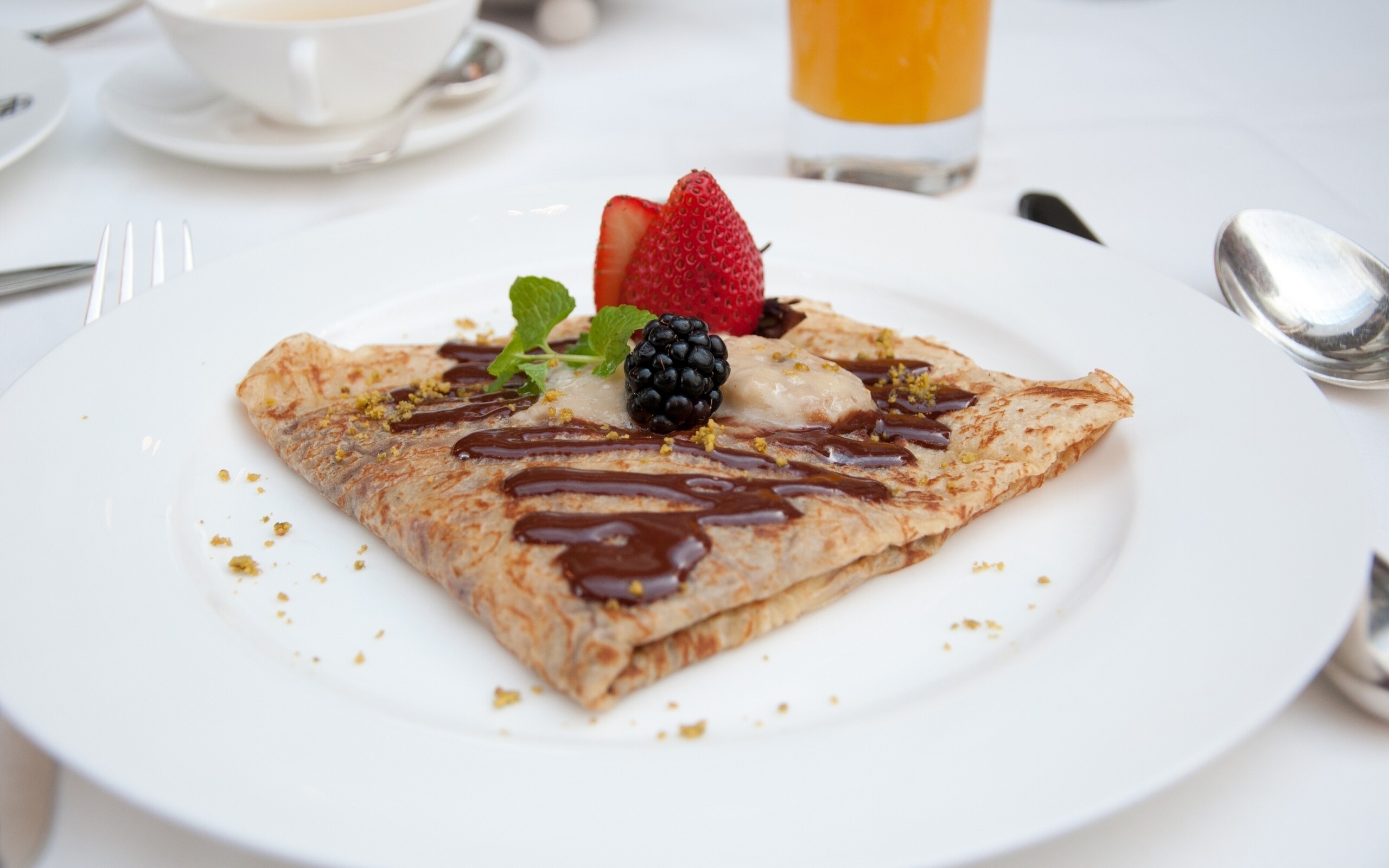 Crepe with chocolate, berries, and mint on a white plate HD Wallpaper