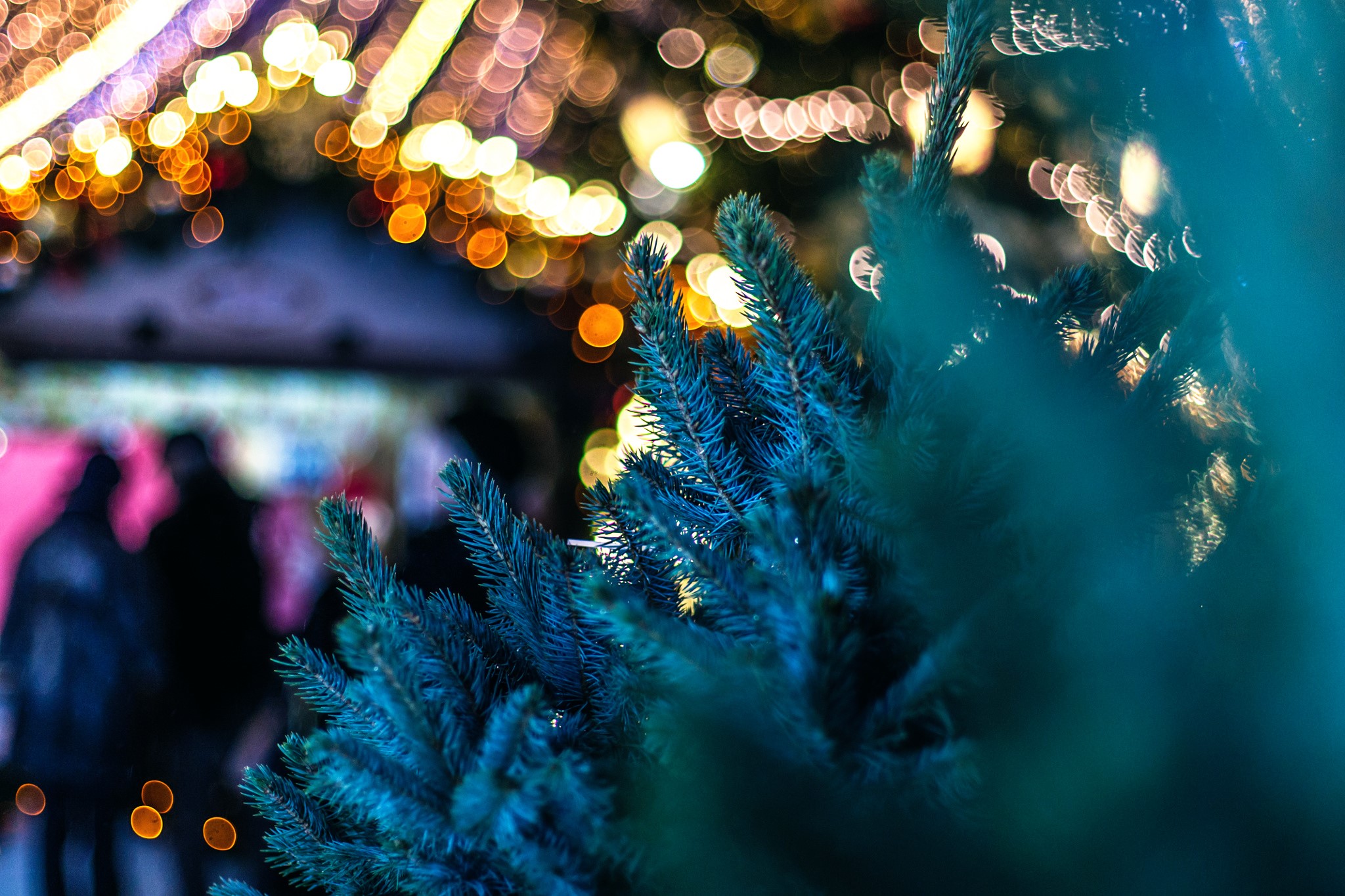 Christmas tree branches with bokeh lights and people HD Wallpaper