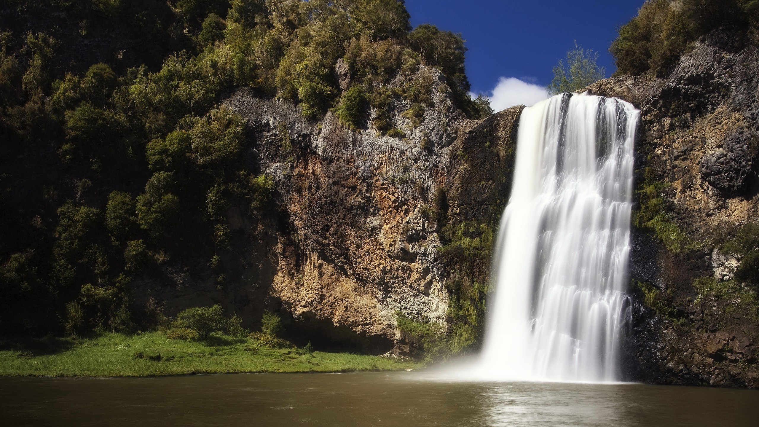 Waterfall cascading over rocky cliffs into a pool HD Wallpaper