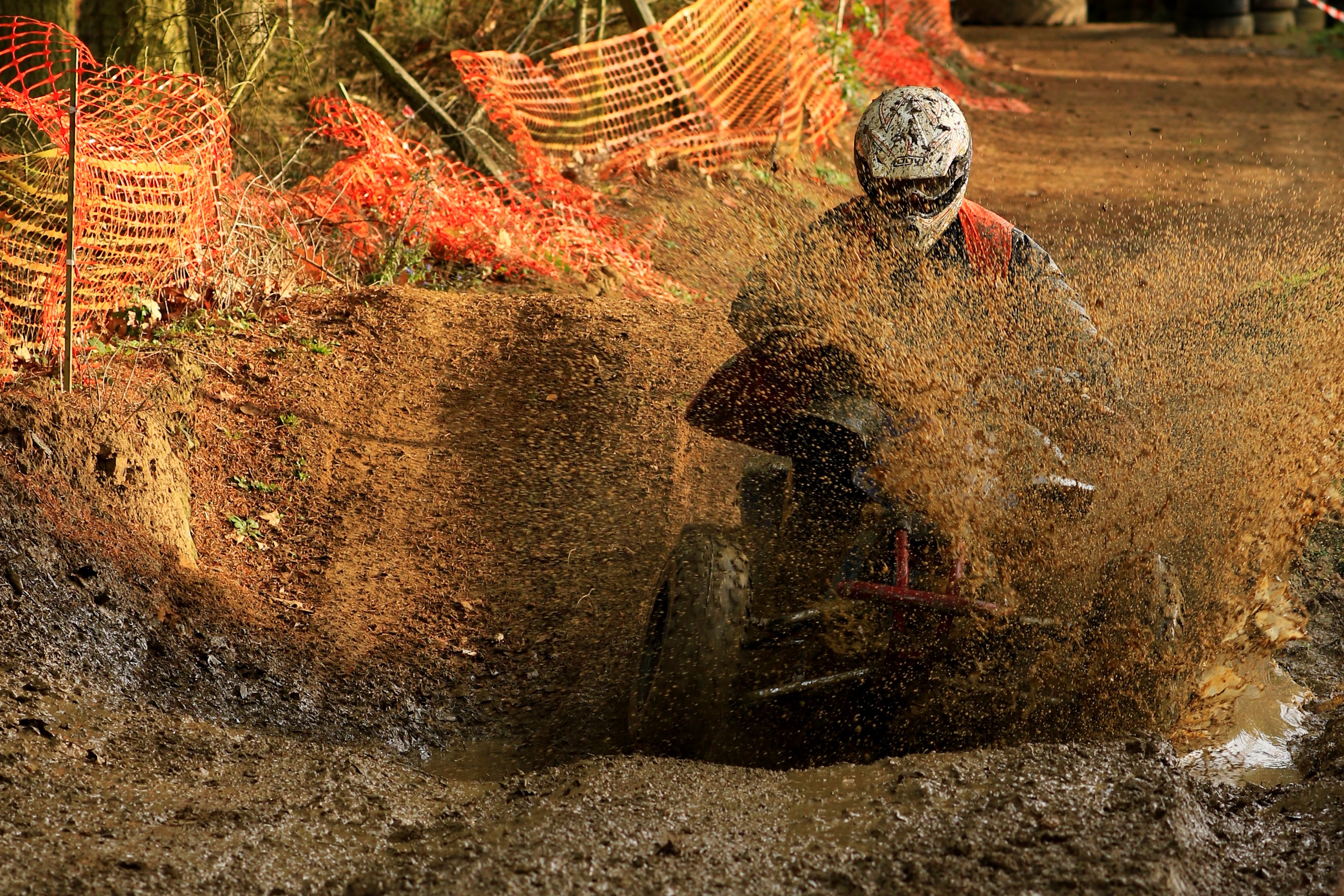 Person riding a quad bike through mud HD Wallpaper