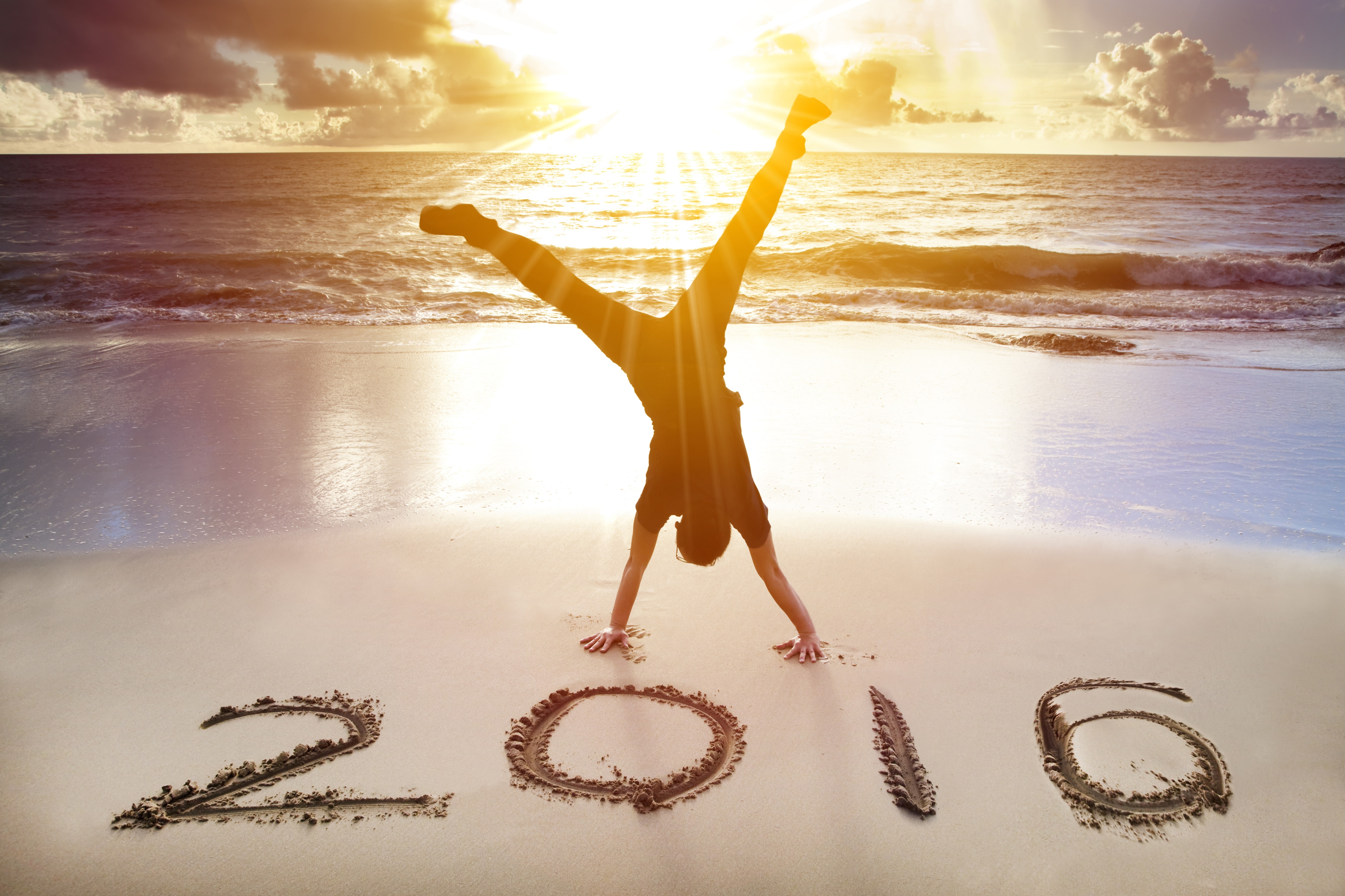 Person doing a handstand on a beach with '2016' written in the sand HD Wallpaper