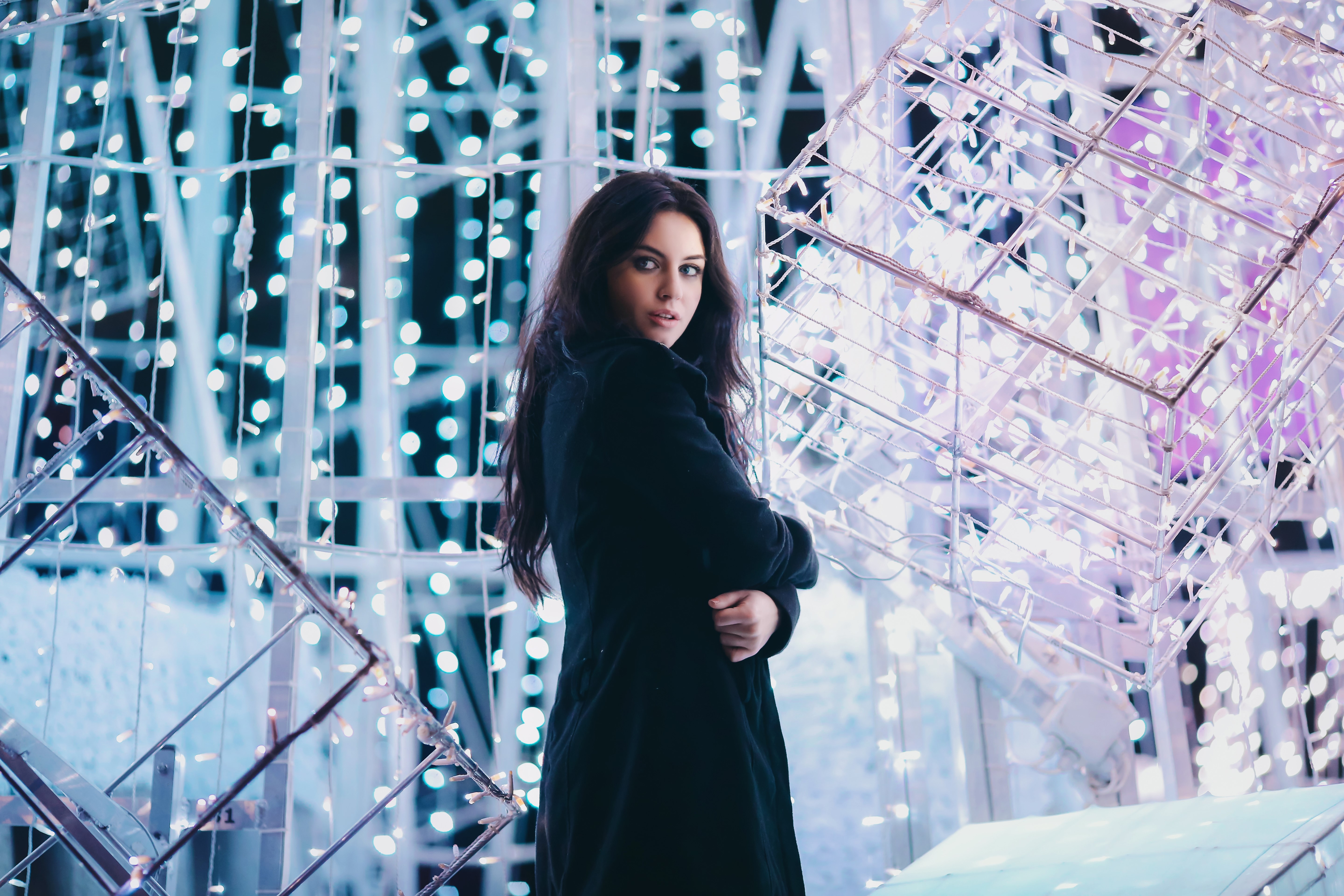Woman in black coat with fairy lights HD Wallpaper