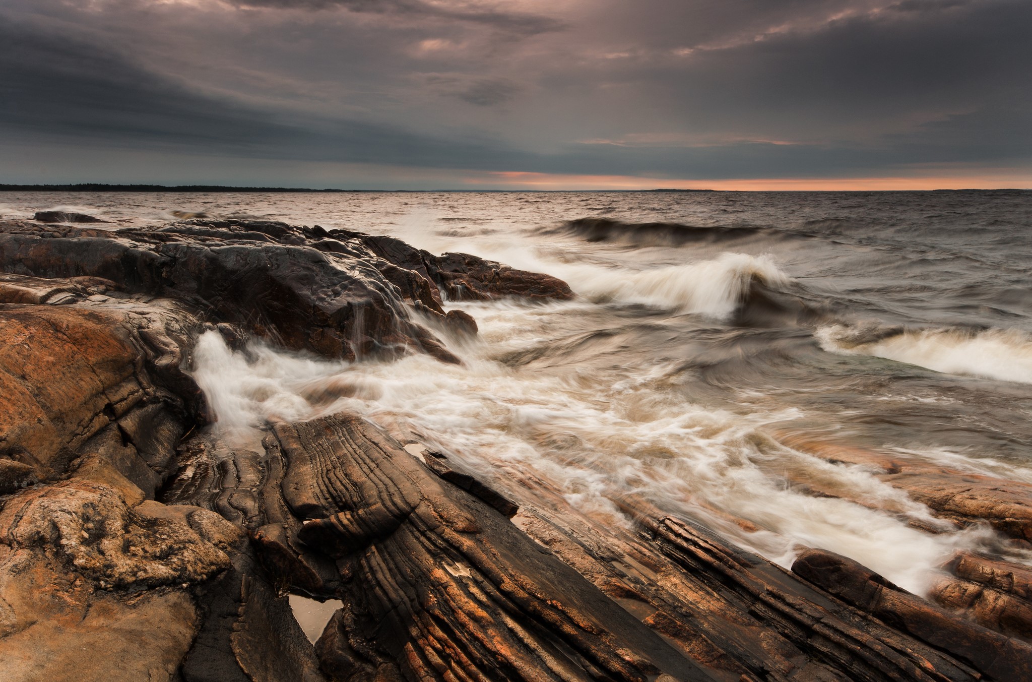Waves crashing on rocky shore at sunset in Varmland, Sweden HD Wallpaper