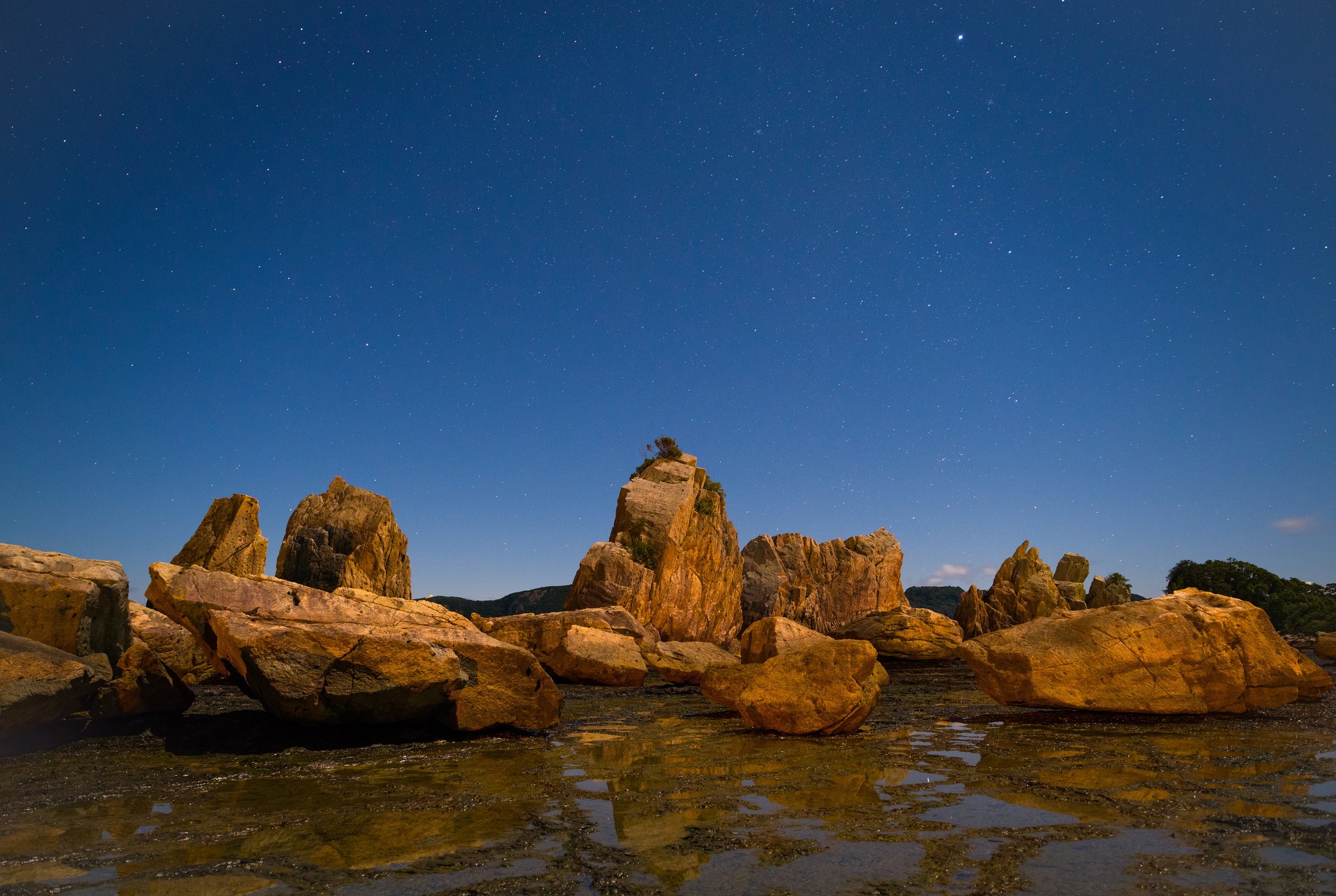 Rocky coast under a starry night sky HD Wallpaper