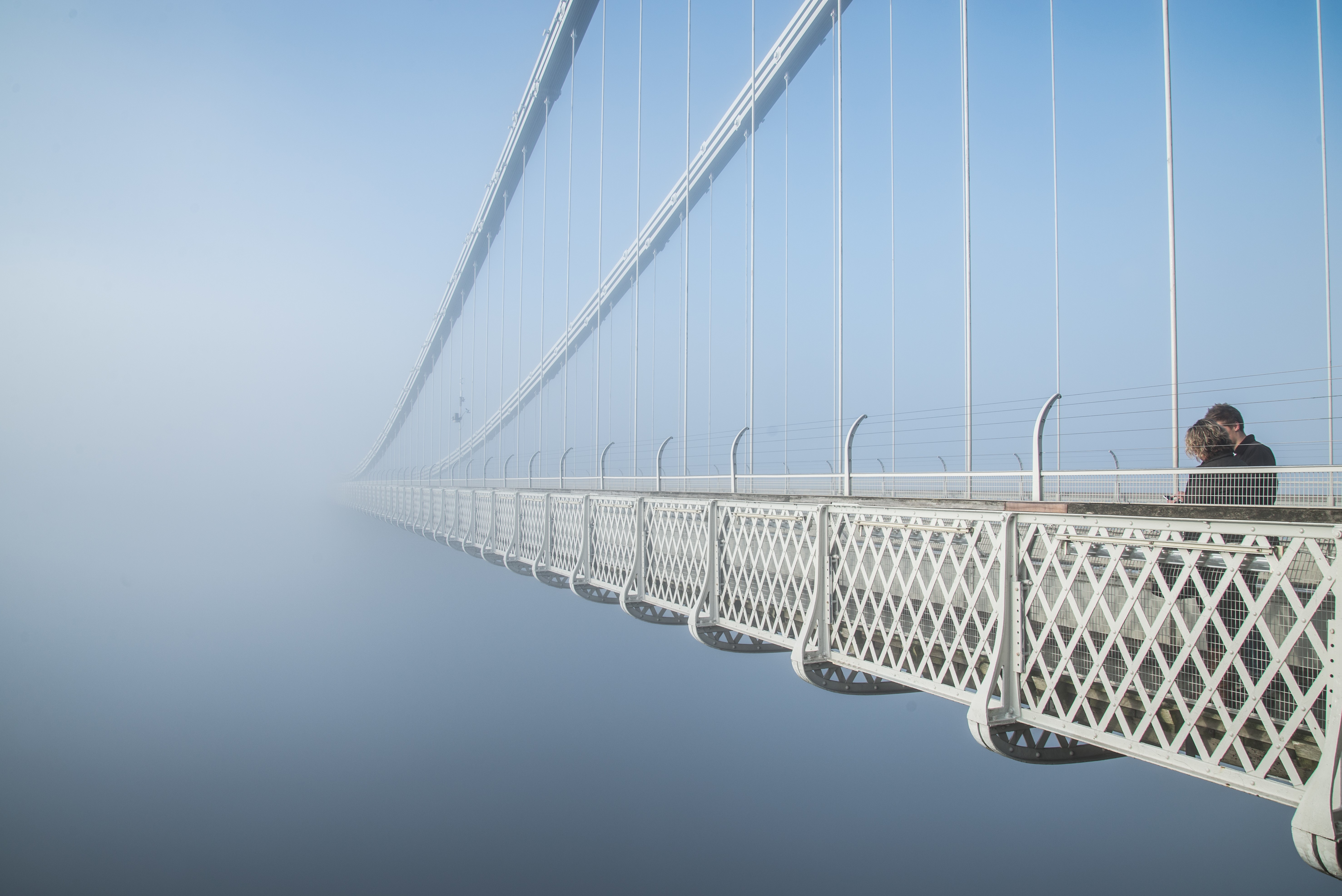 Couple on a suspension bridge in fog HD Wallpaper