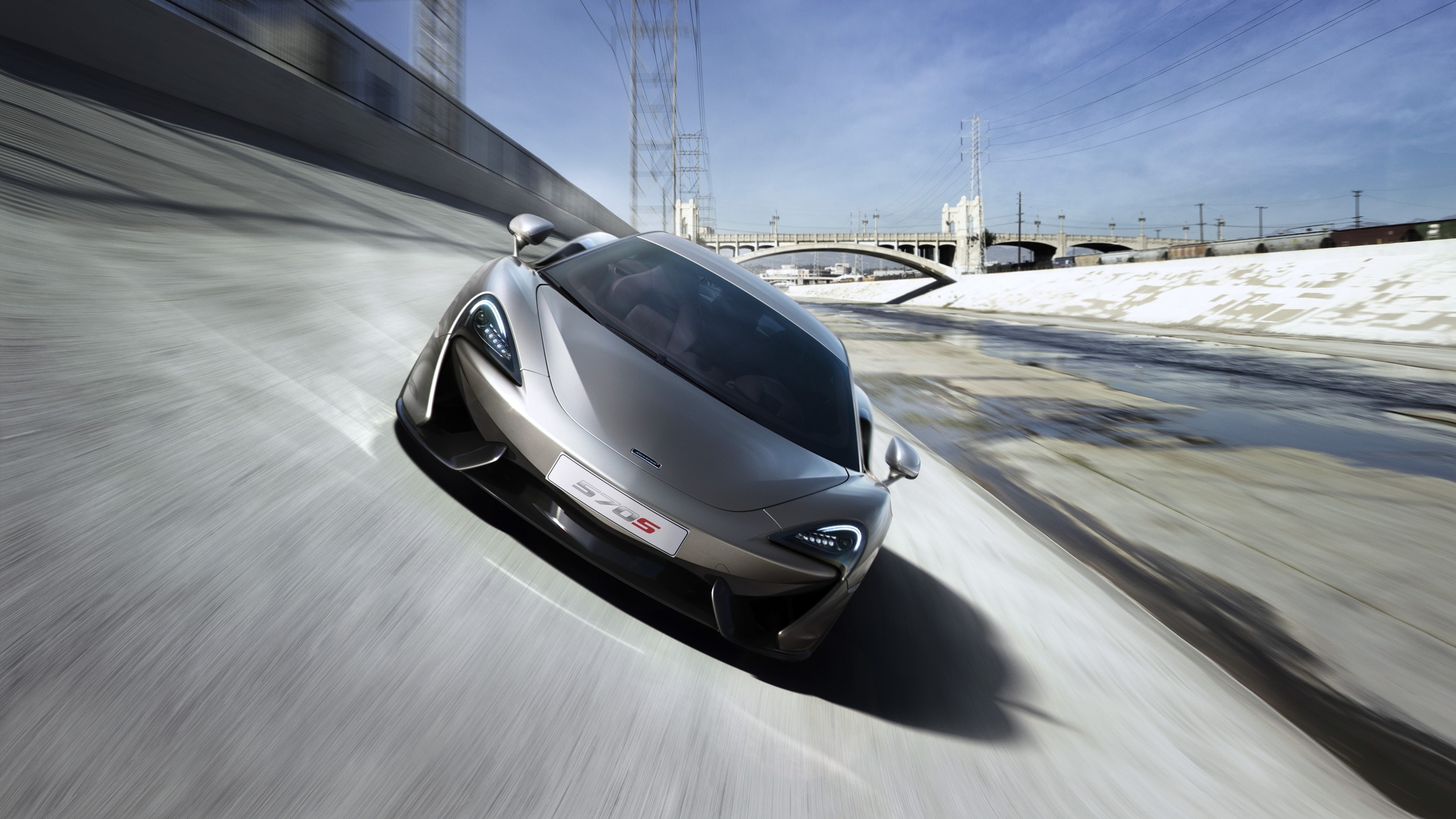 McLaren 570S Coupe driving on a concrete riverbed HD Wallpaper