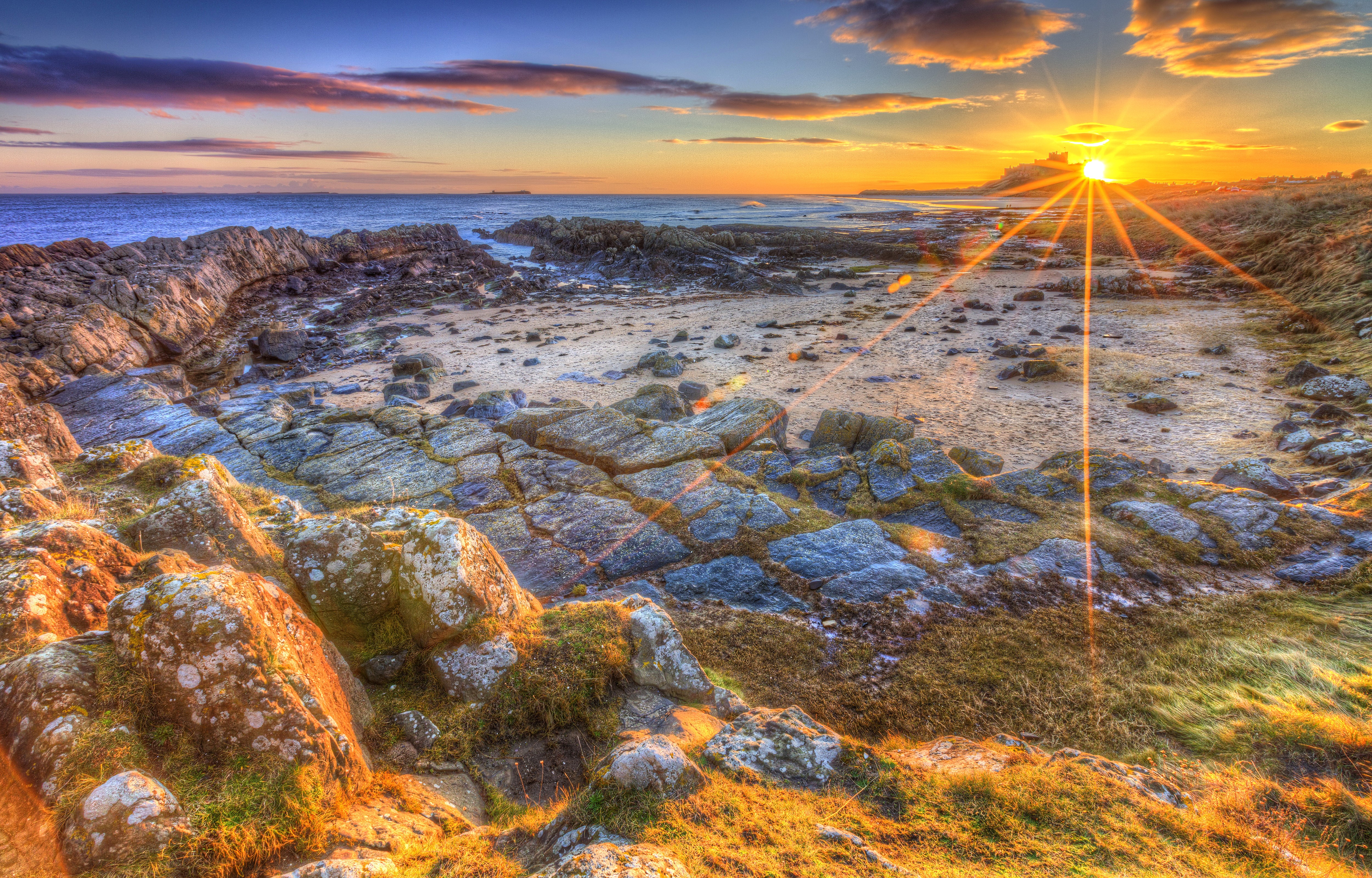 Sunset over rocky coast with sun rays and clouds HD Wallpaper