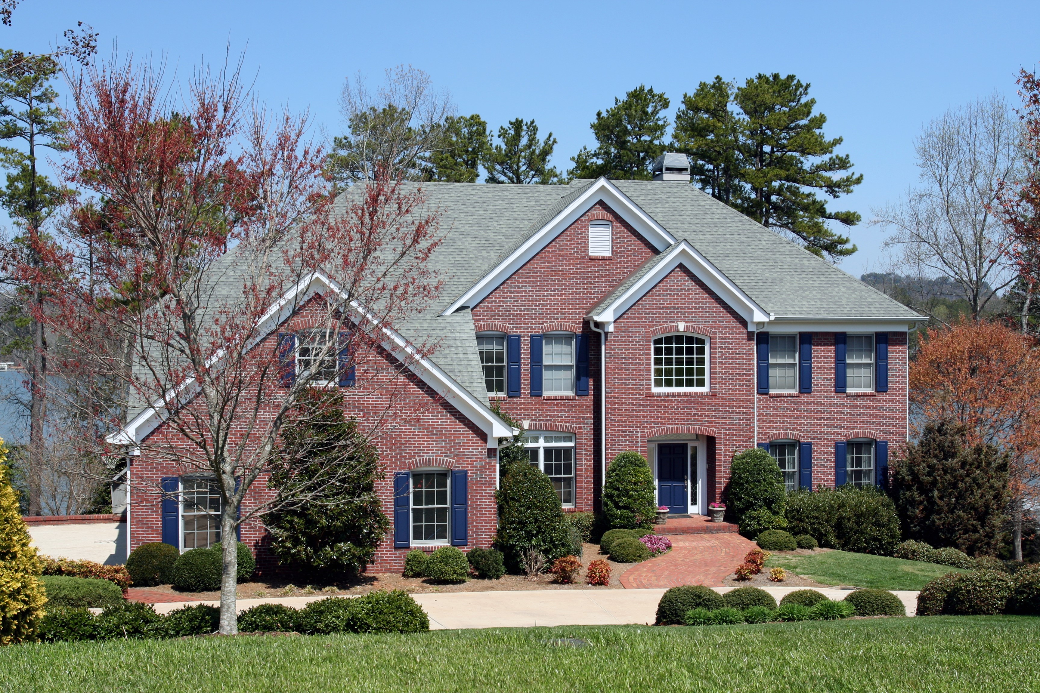 Red brick house with blue shutters and trees HD Wallpaper