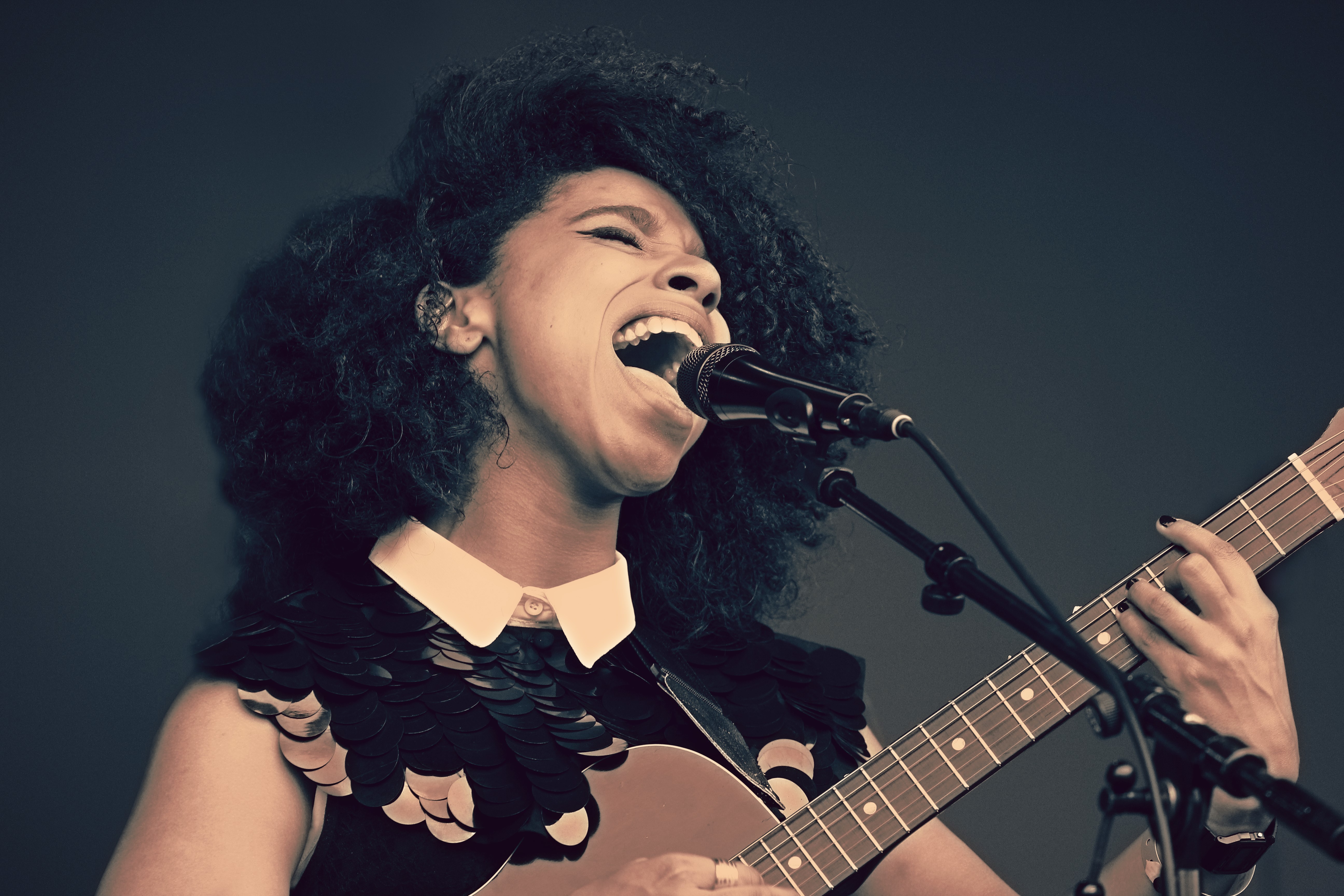 Woman singing into microphone playing guitar HD Wallpaper