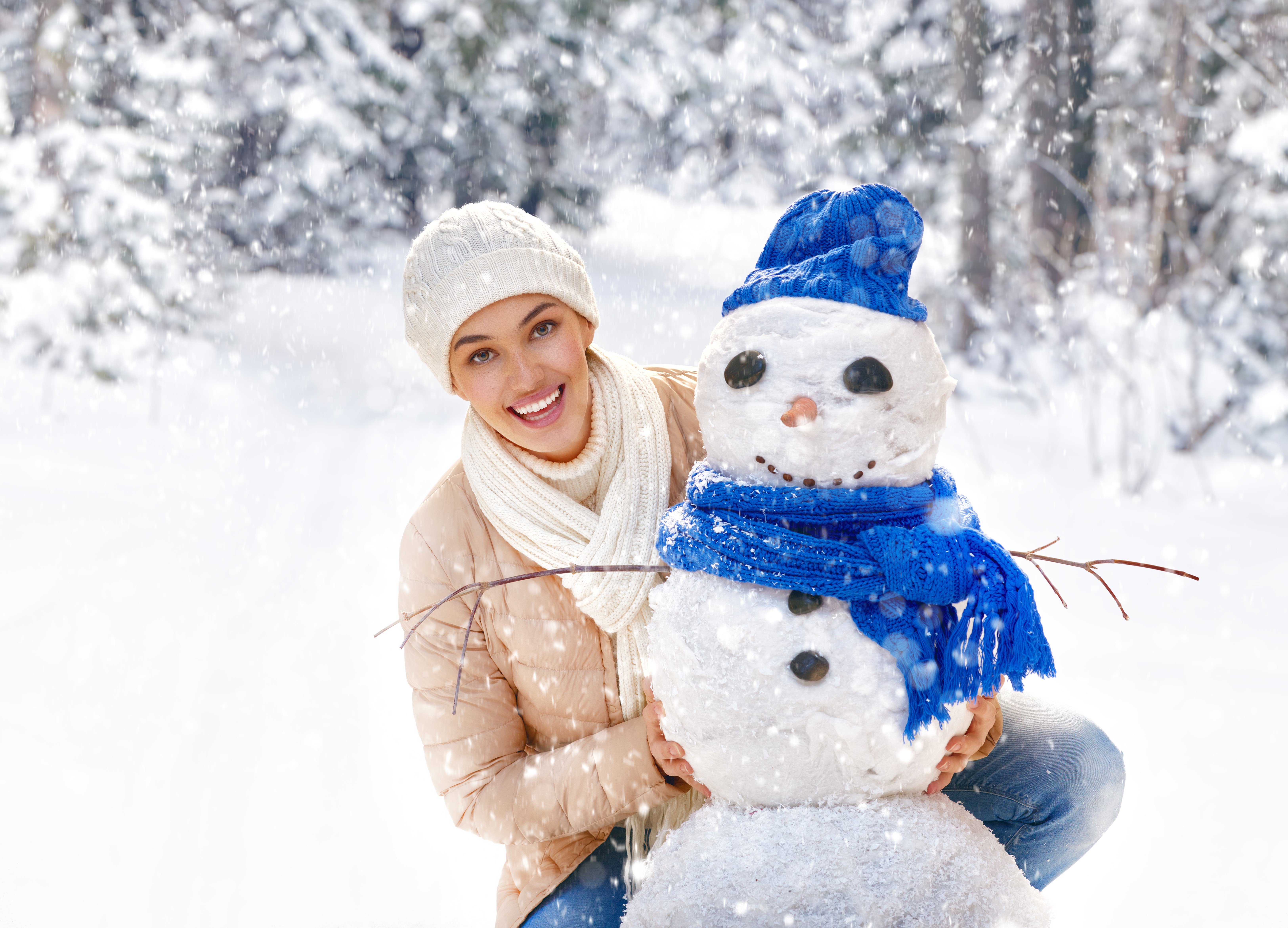 Woman building a snowman in a snowy forest HD Wallpaper