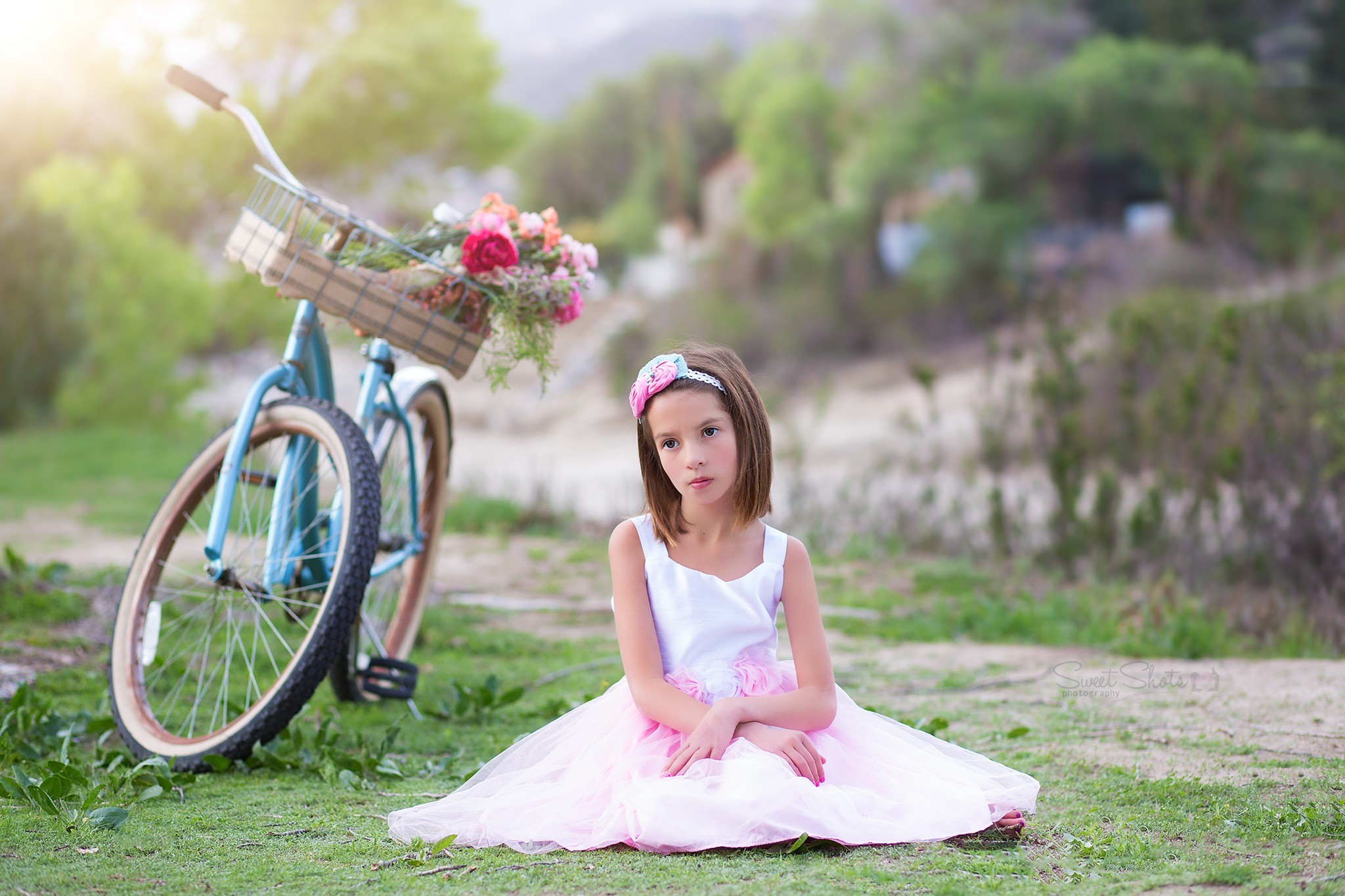 Girl in pink dress sitting by a bicycle with flowers HD Wallpaper