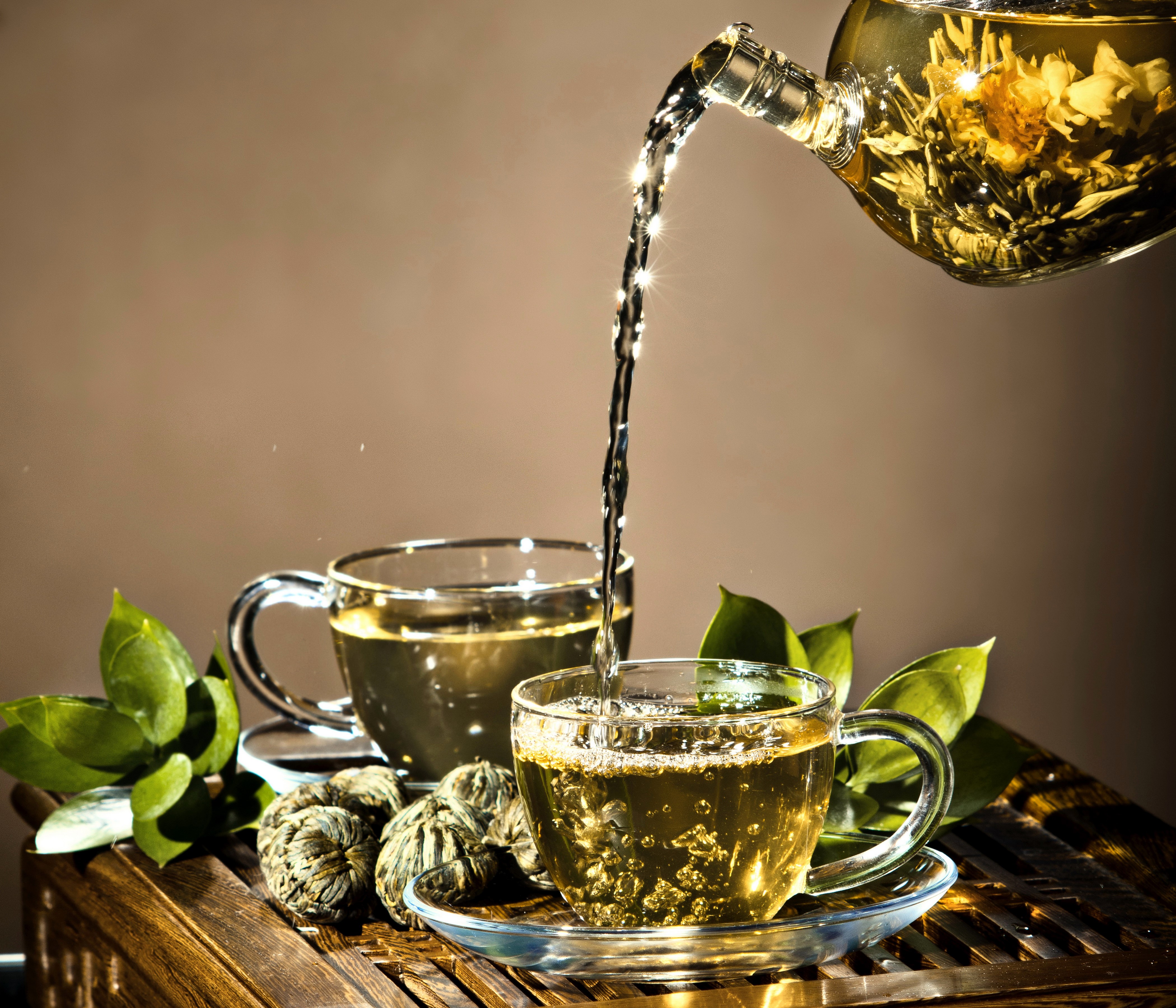 Tea being poured into a cup with tea leaves HD Wallpaper