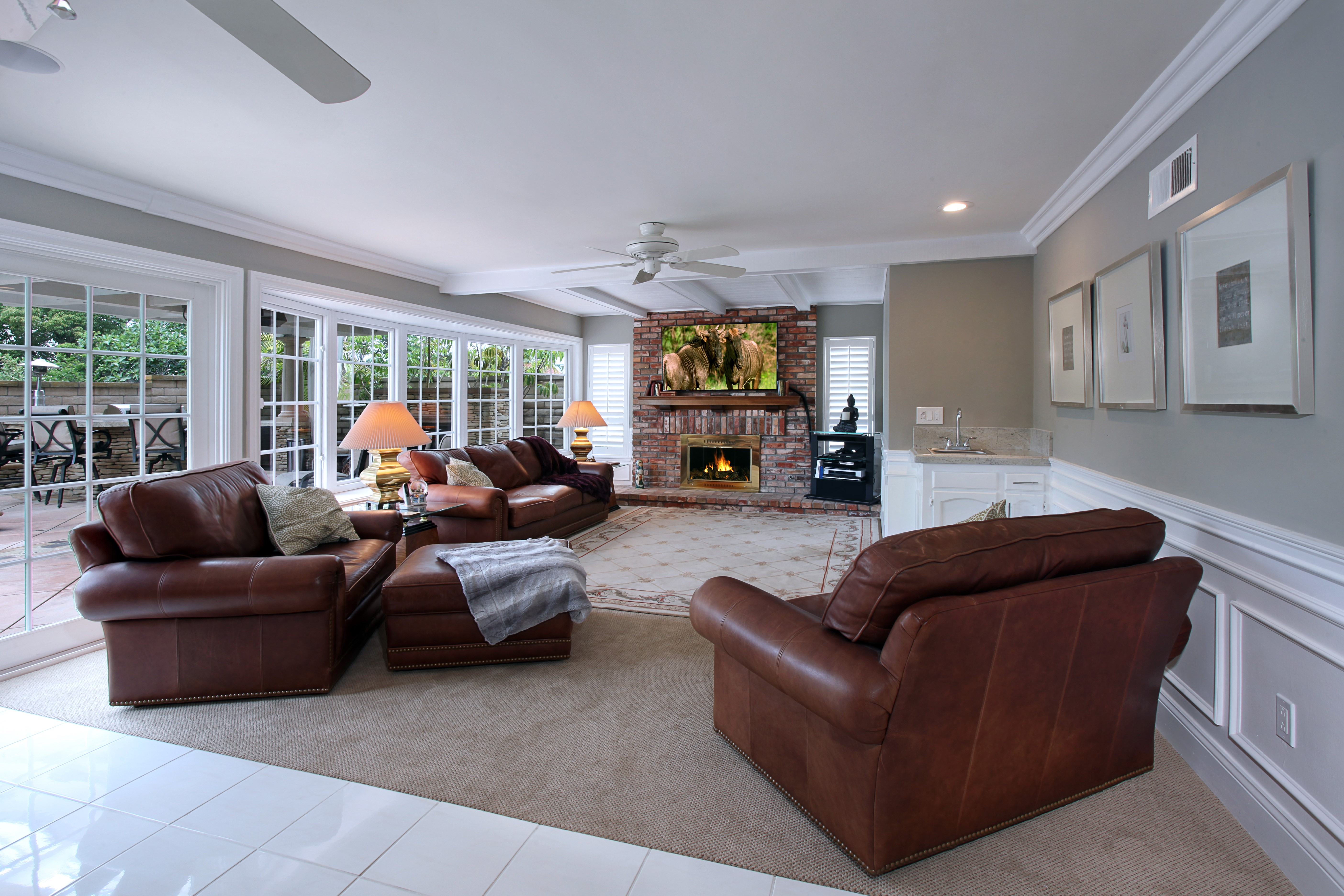Living room with leather sofas, fireplace, and large windows HD Wallpaper