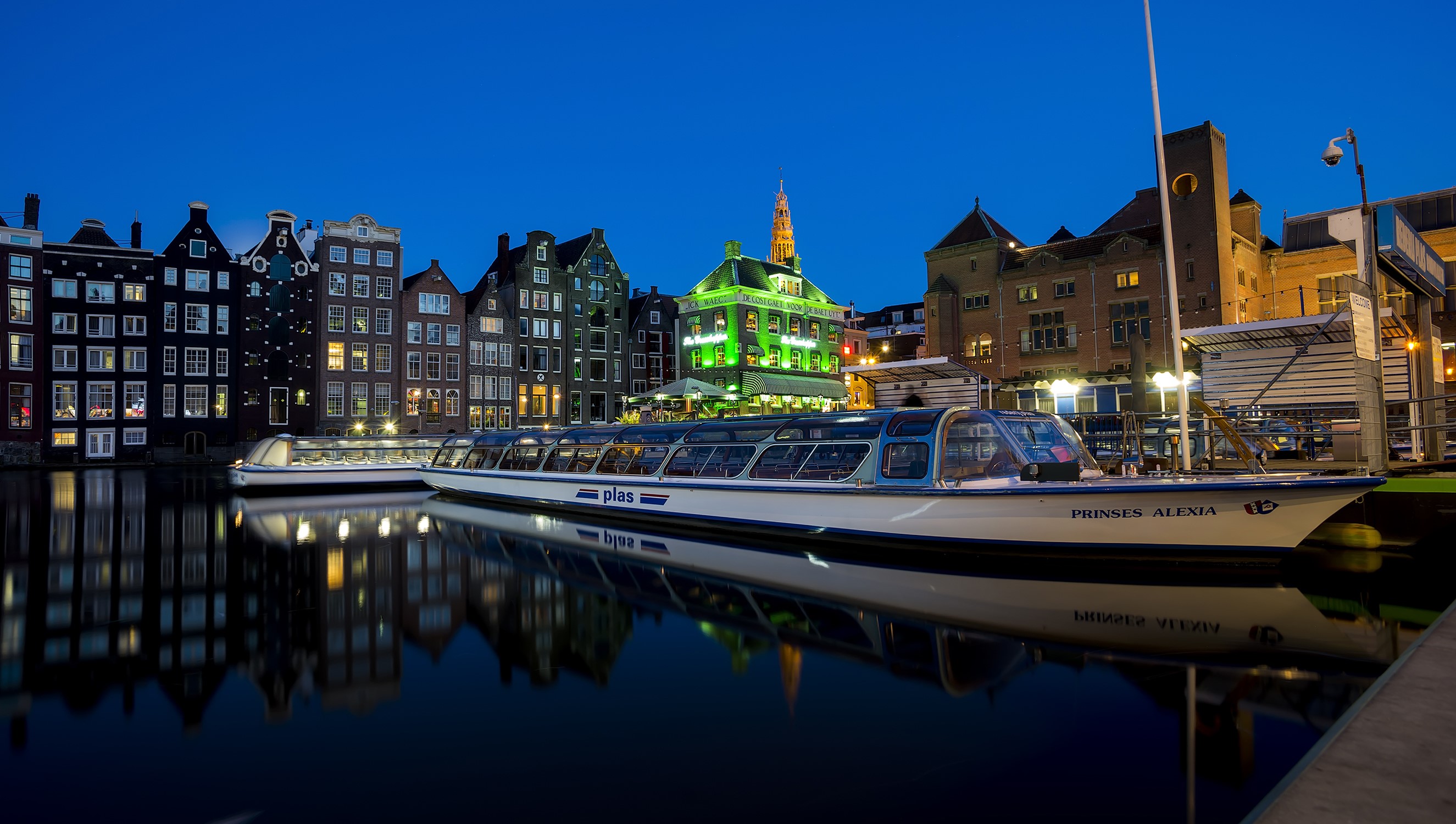 Amsterdam canal at night with riverboats and houses HD Wallpaper