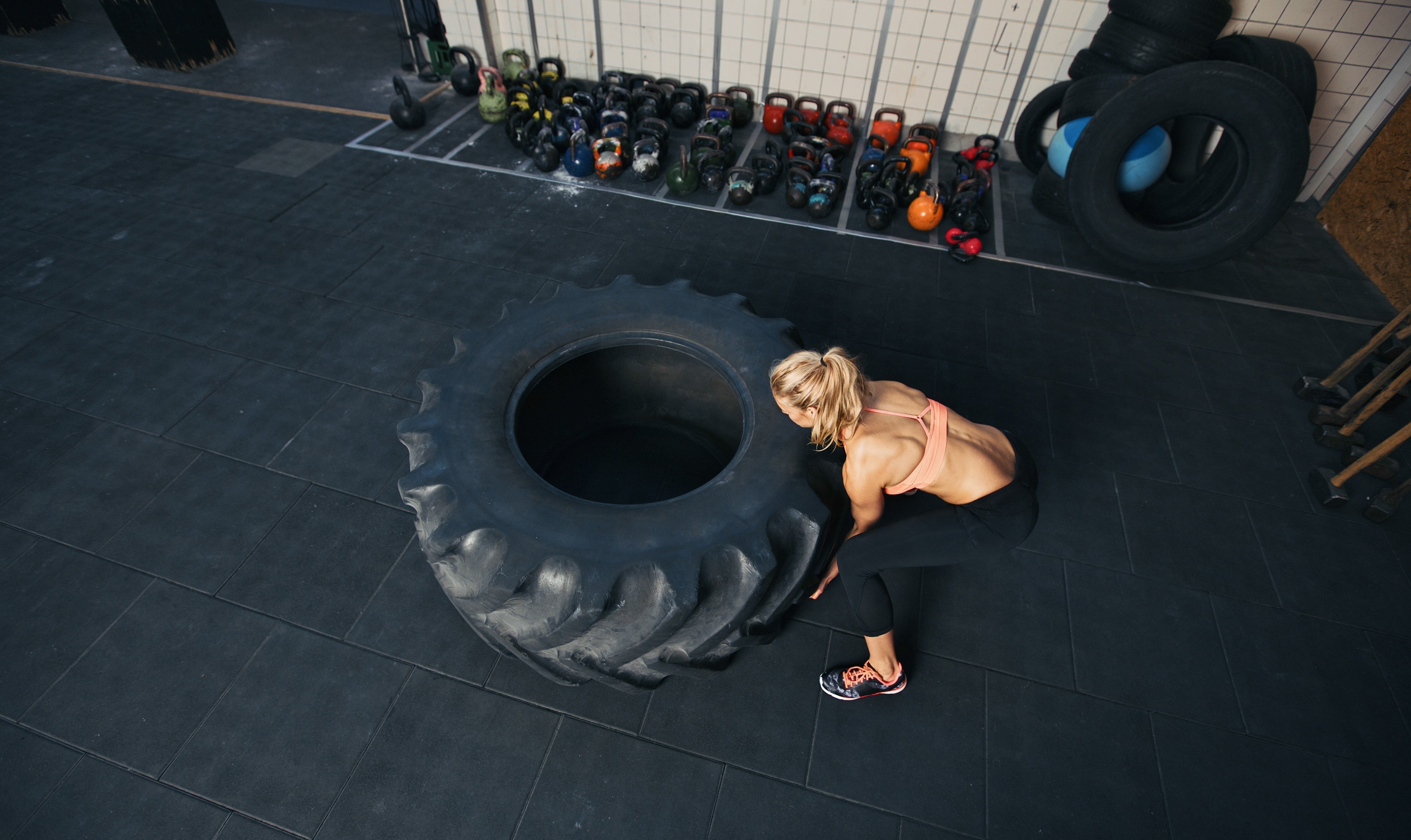 Woman flipping a large tire in a gym HD Wallpaper
