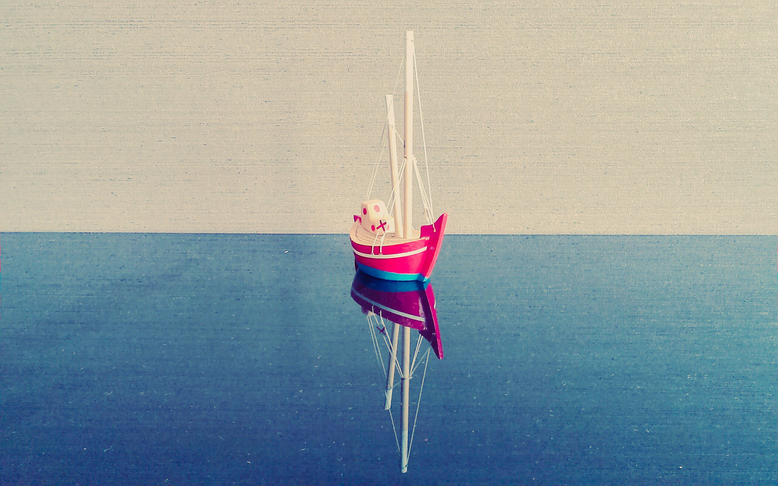 Toy sailboat on reflective surface HD Wallpaper