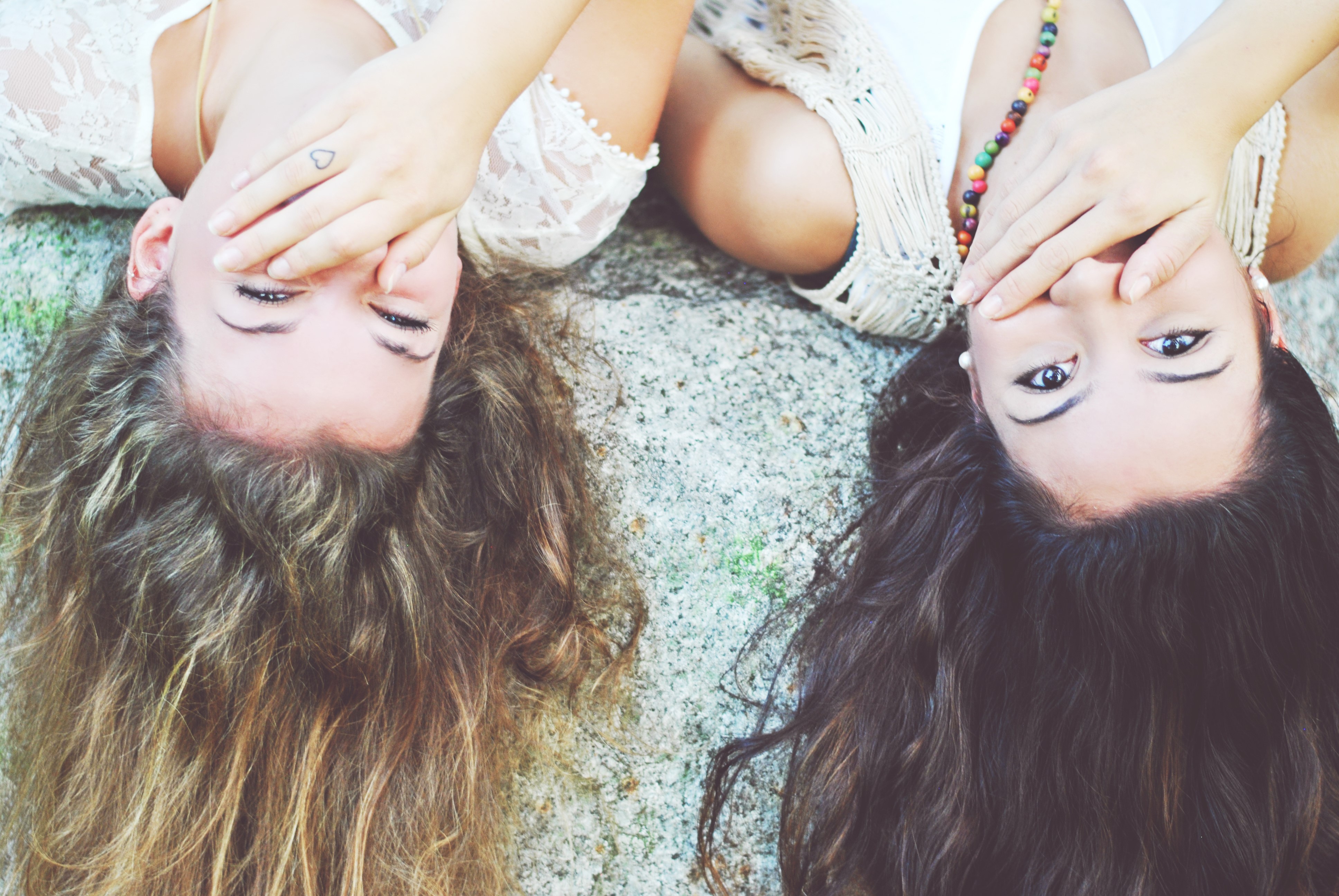 Two girls lying down covering faces HD Wallpaper
