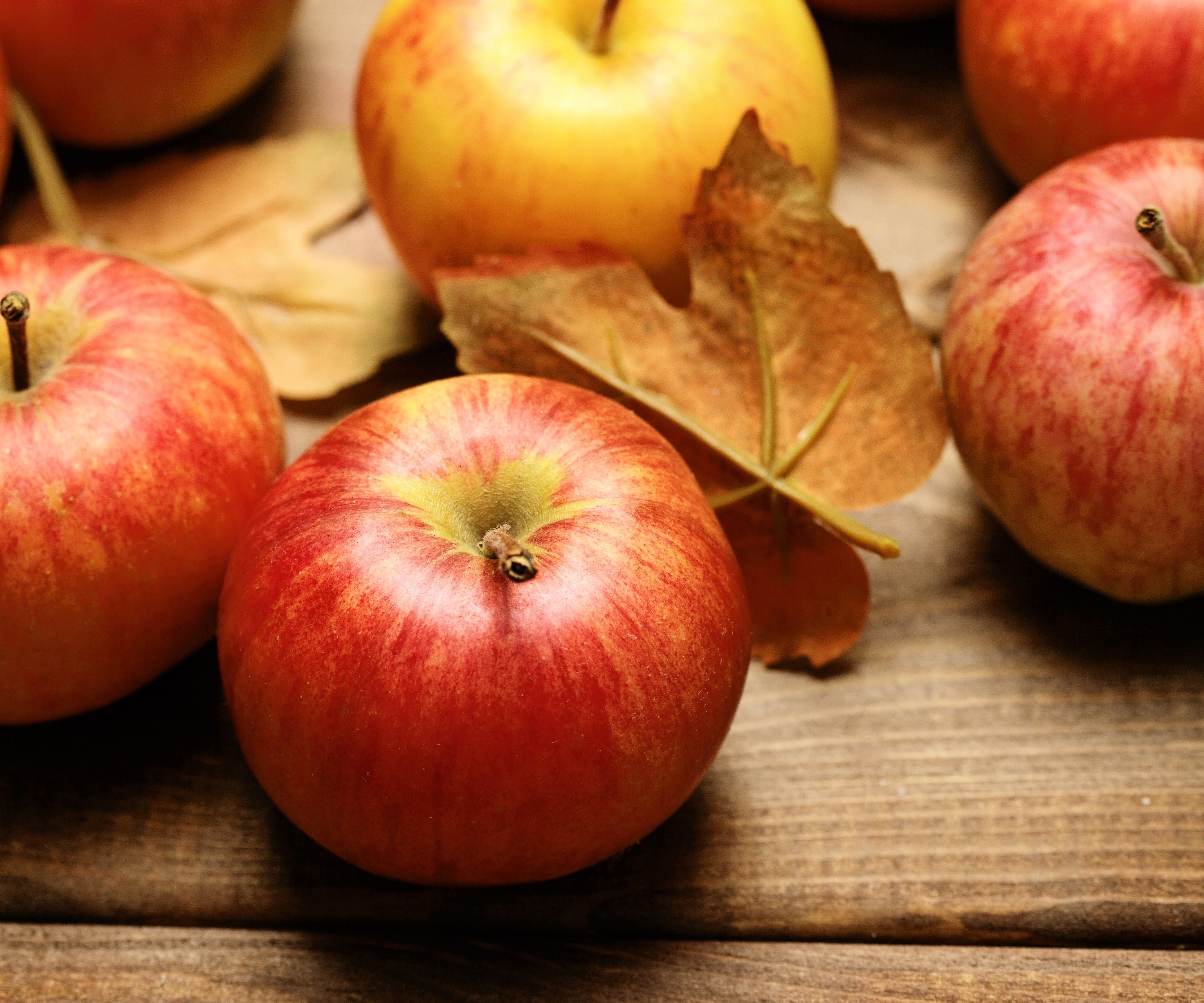 Apples and autumn leaves on a wooden surface HD Wallpaper