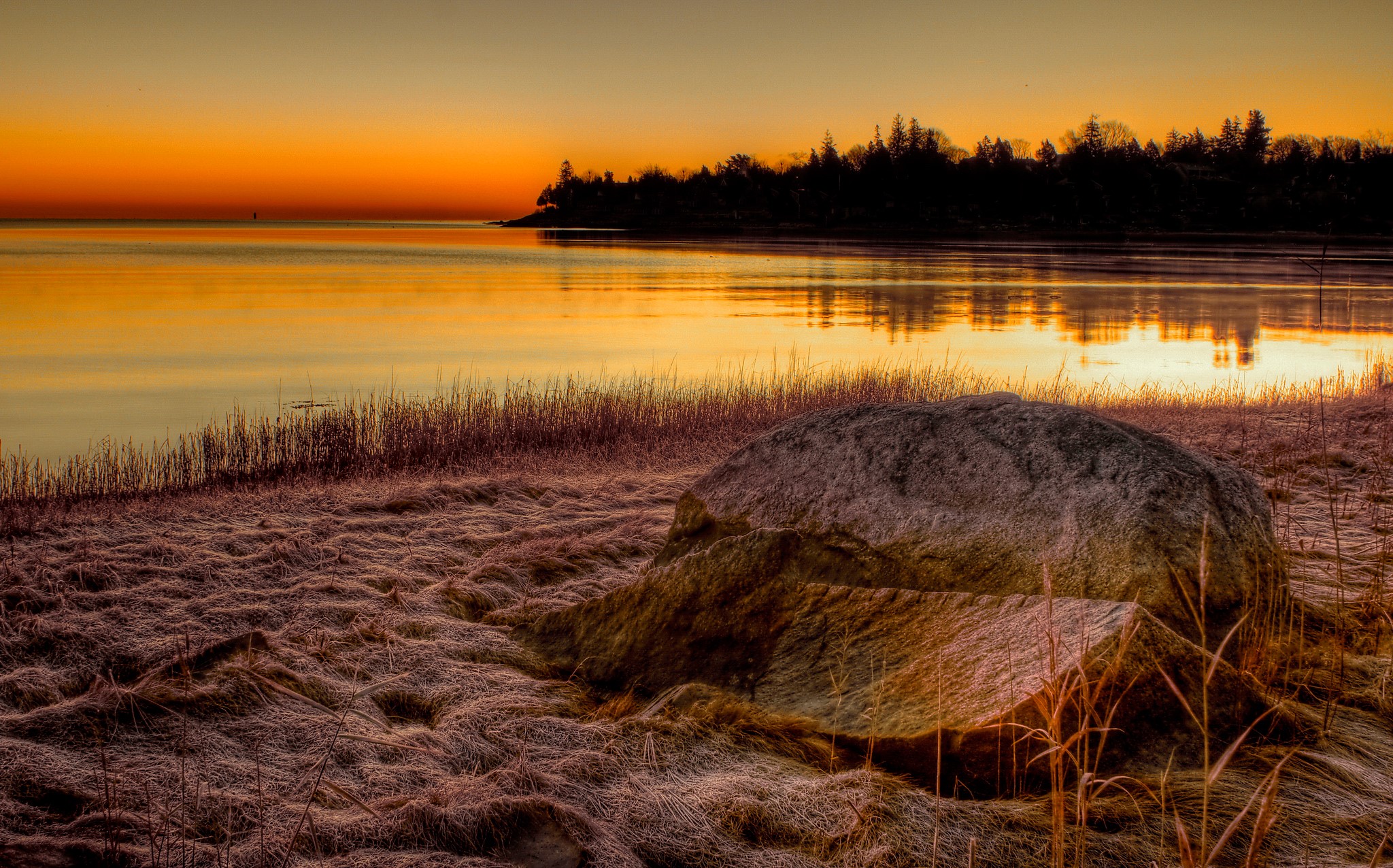 Sunrise over a calm lake with a rocky shore HD Wallpaper