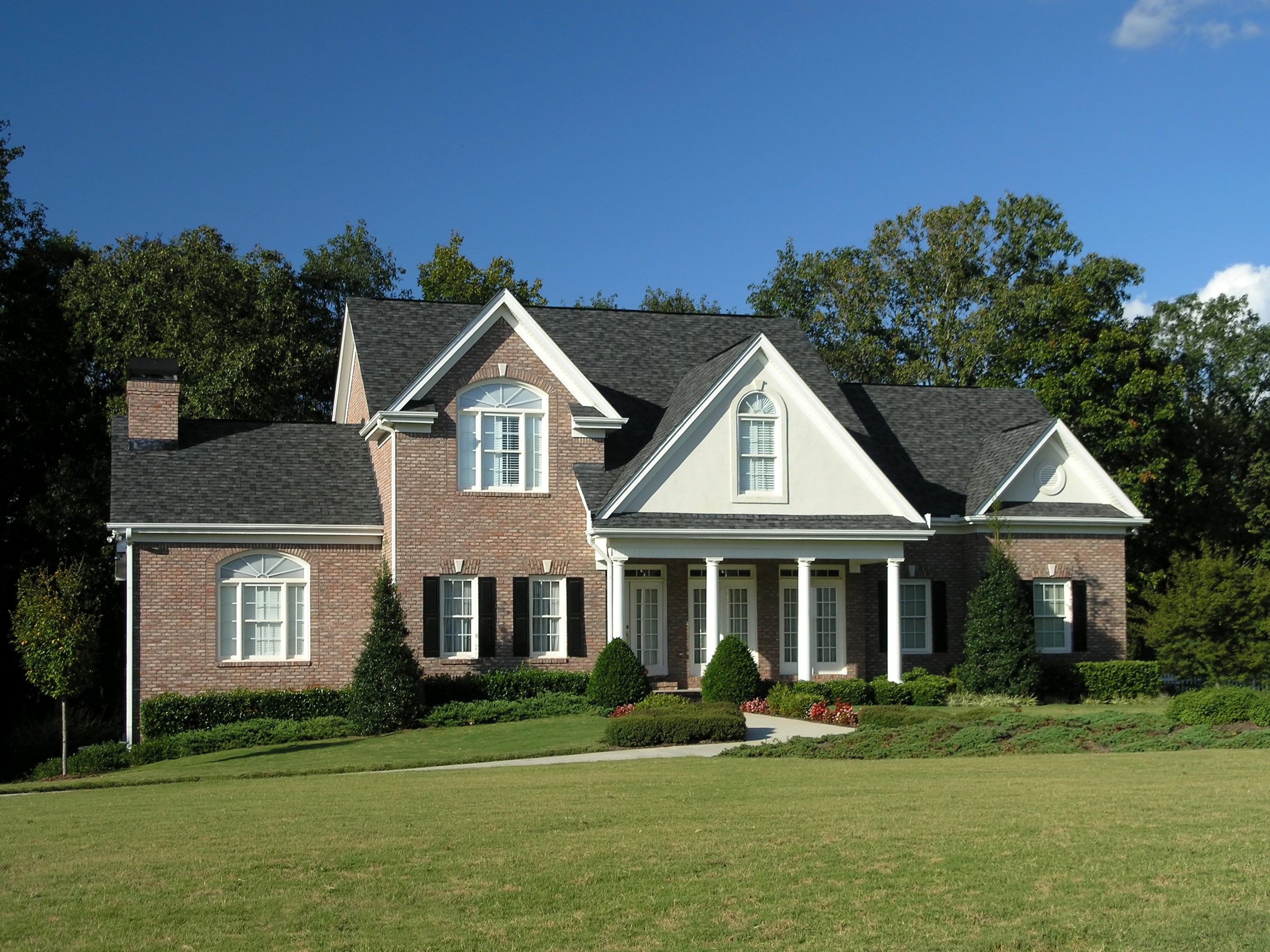 Brick house with white columns and manicured lawn HD Wallpaper