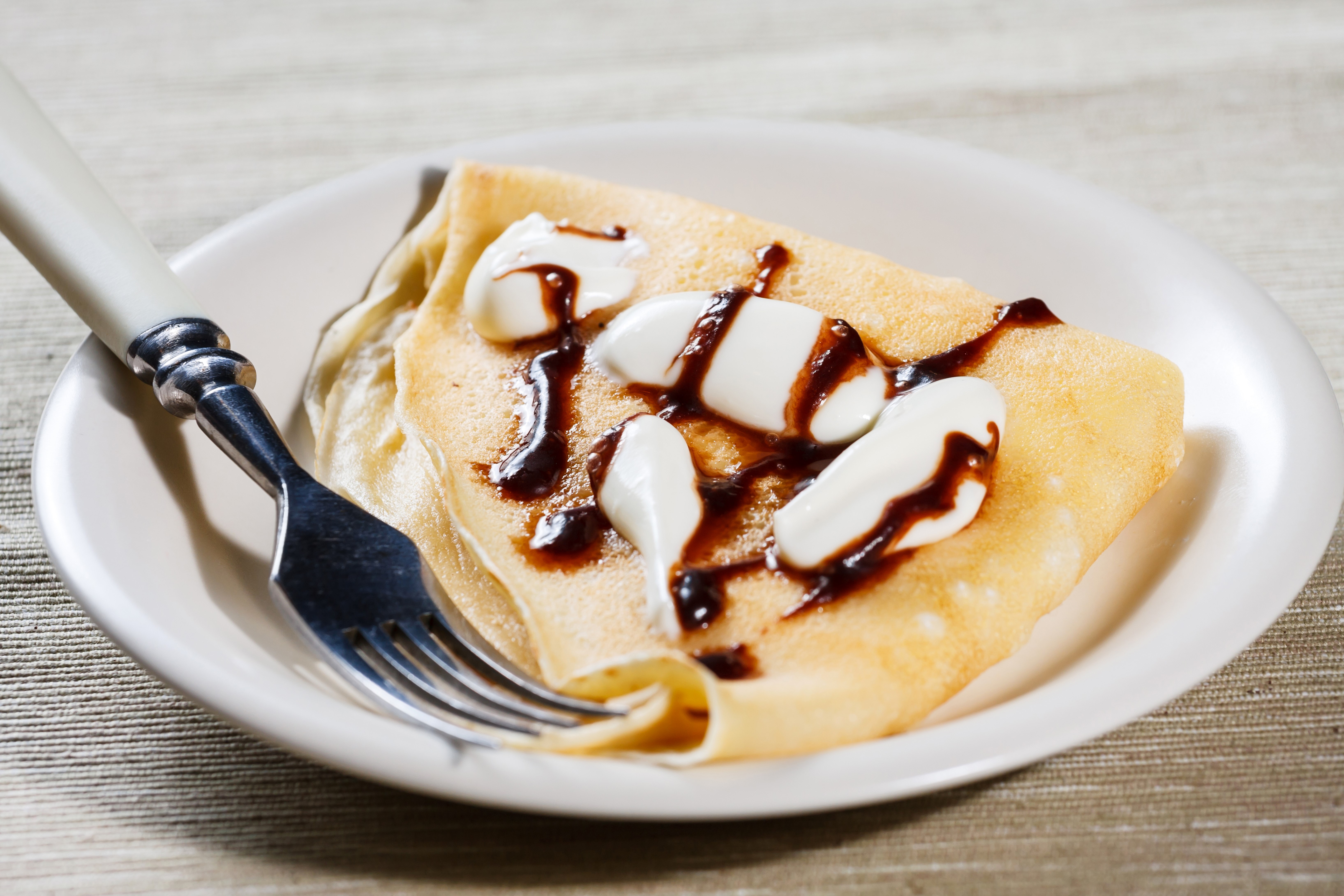 Pancake with cream and chocolate sauce on a plate with a fork HD Wallpaper