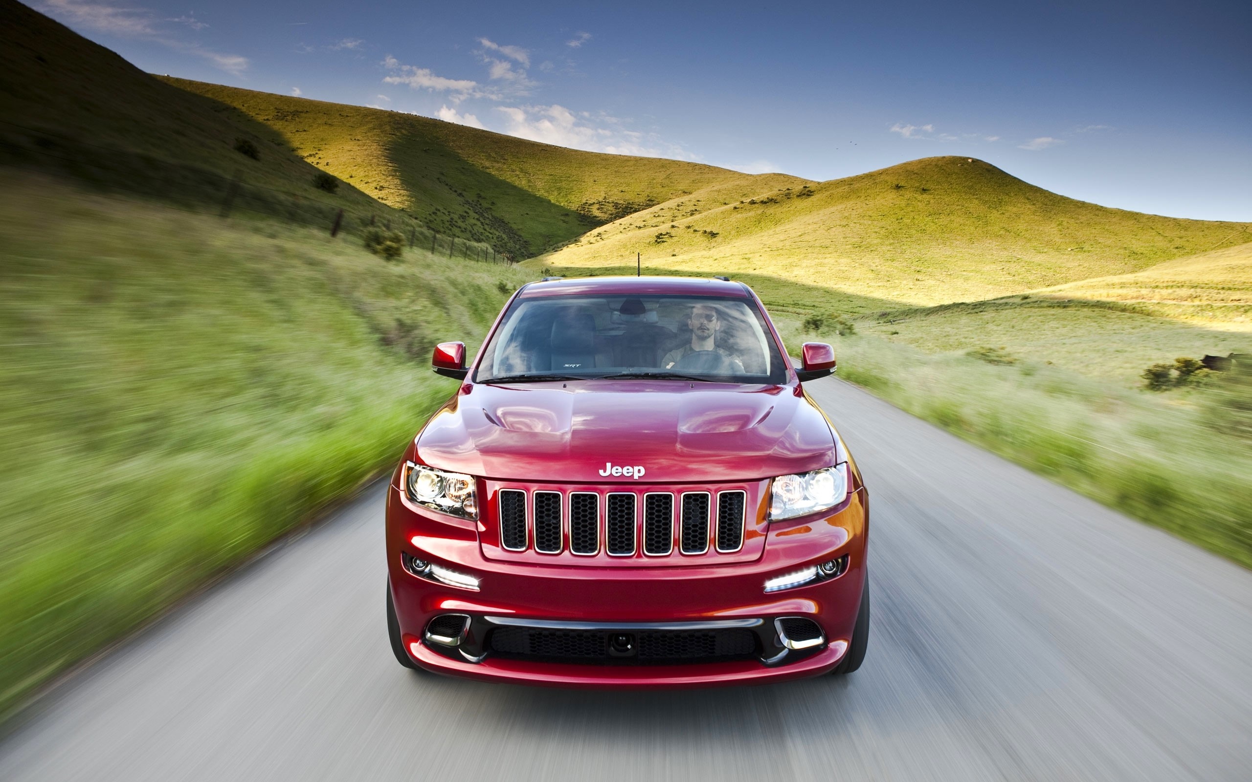 Red Jeep Grand Cherokee driving on a scenic road HD Wallpaper