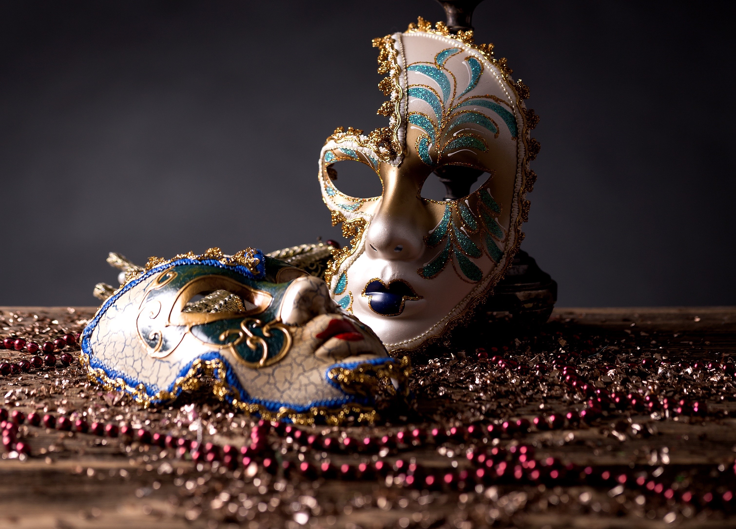 Two Venetian masks on a wooden table with beads HD Wallpaper