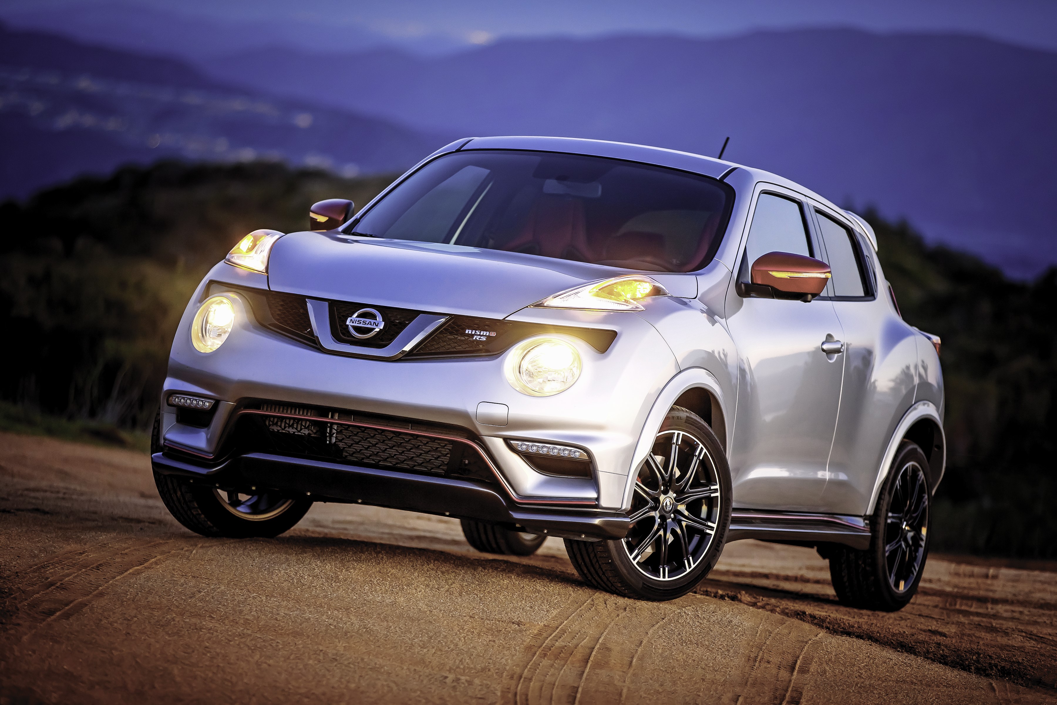 Silver Nissan Juke Nismo RS on a dirt road at dusk HD Wallpaper
