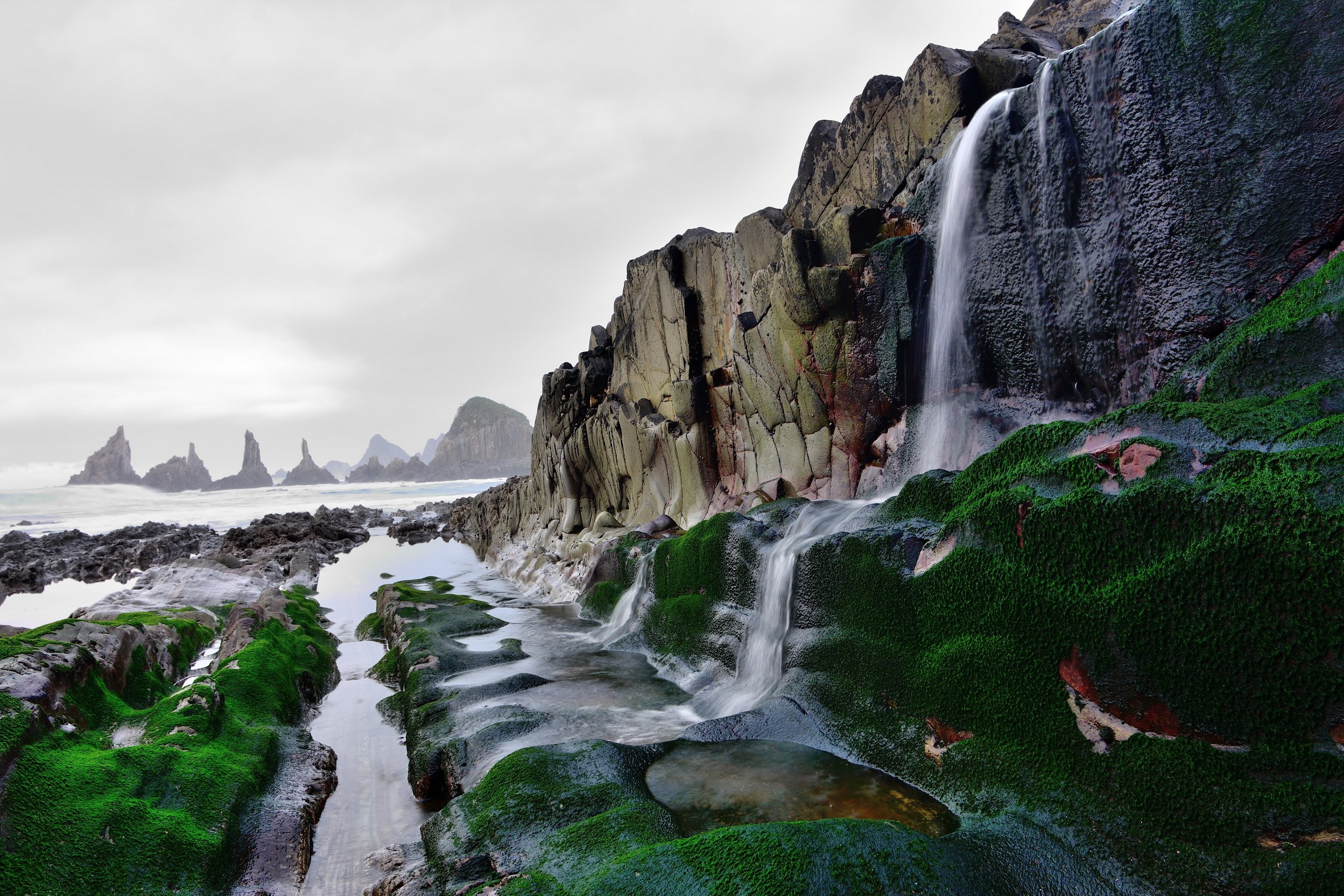 Waterfall cascading over moss-covered rocks in Asturias, Spain HD Wallpaper