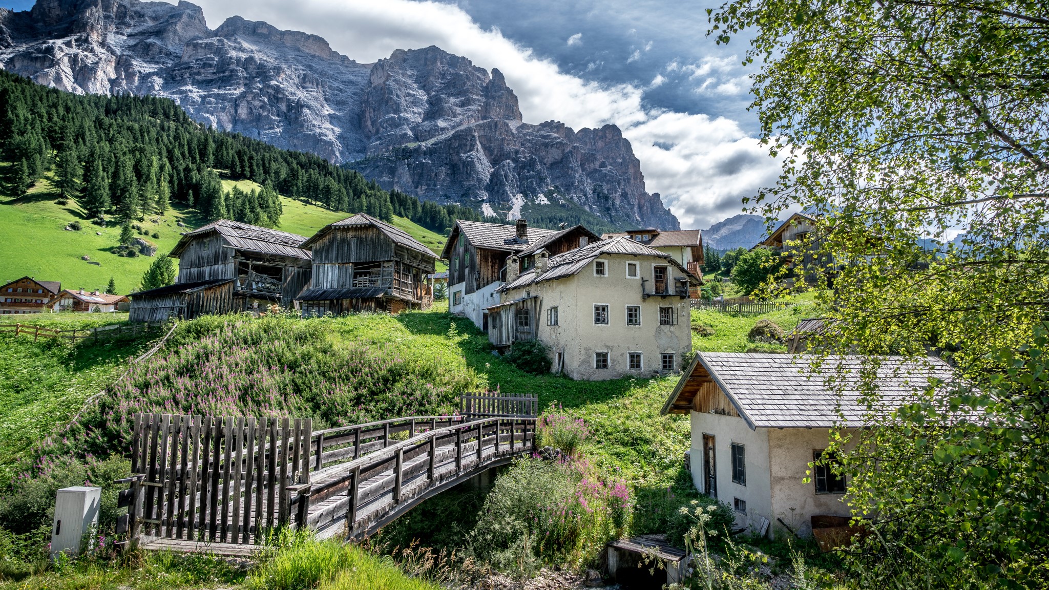 Houses and bridge in San Cassiano Alta Badia, Italy, with mountains HD Wallpaper