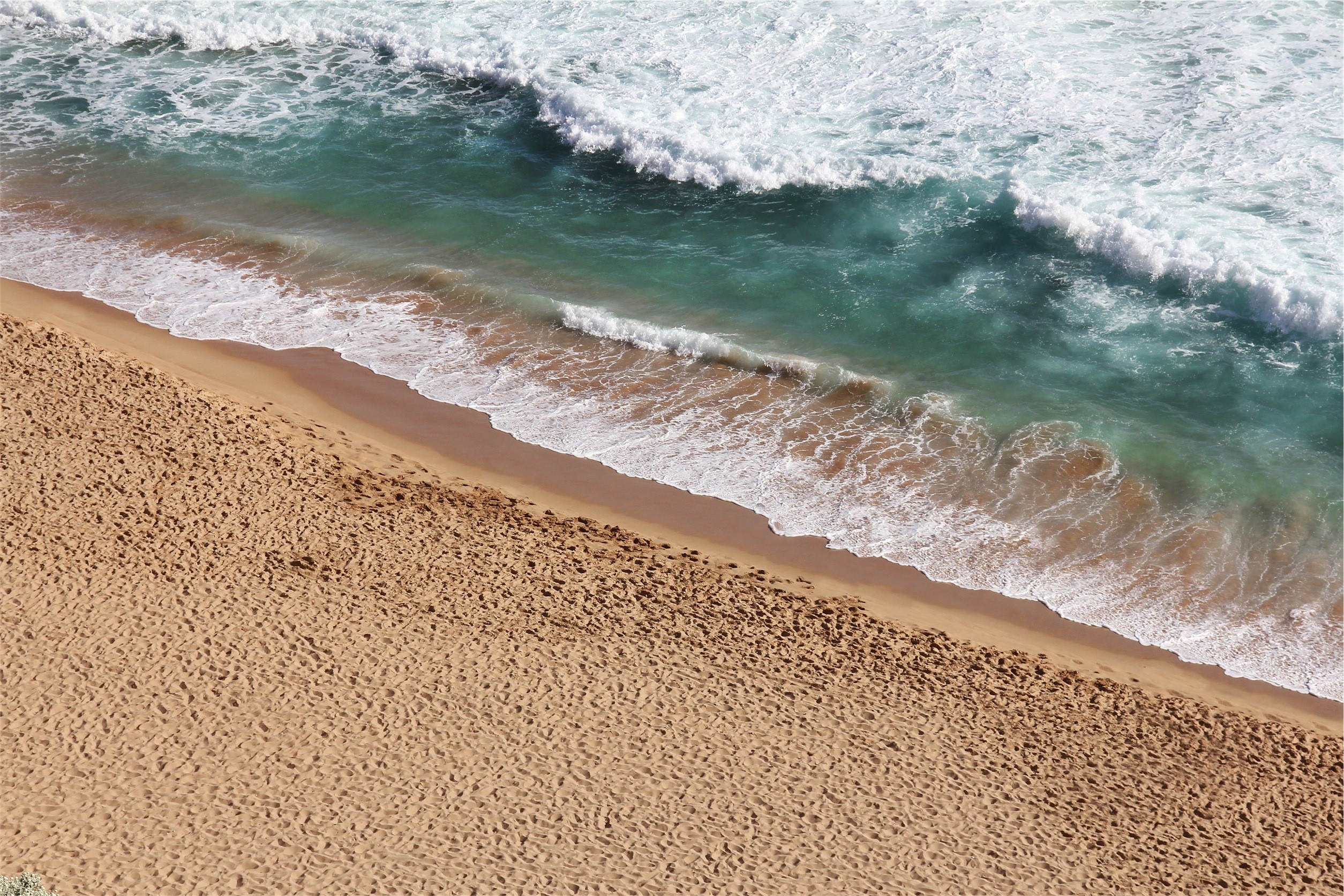 Ocean waves crashing on a sandy beach HD Wallpaper