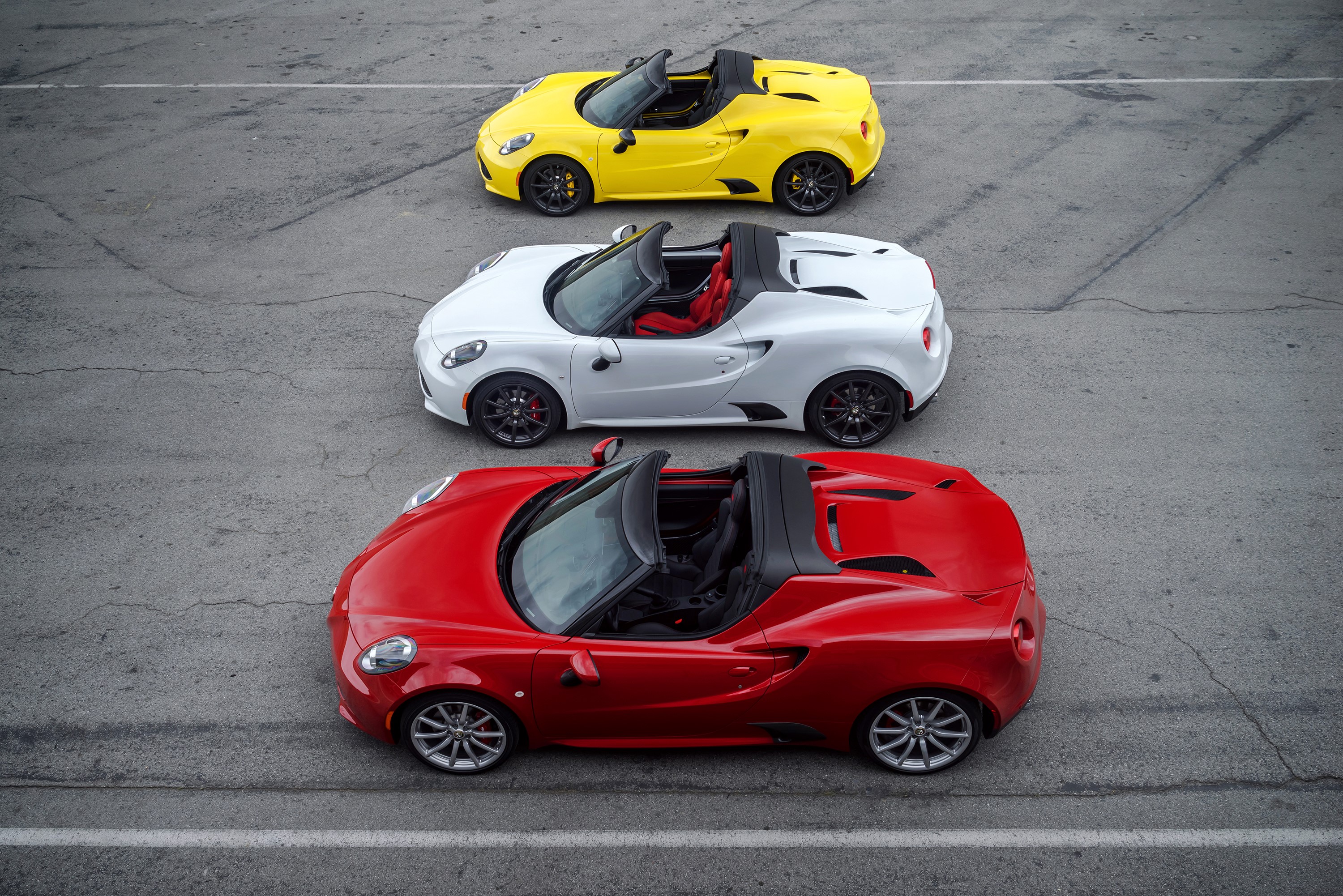 Three Alfa Romeo 4C Spider convertibles in yellow, white, and red HD Wallpaper