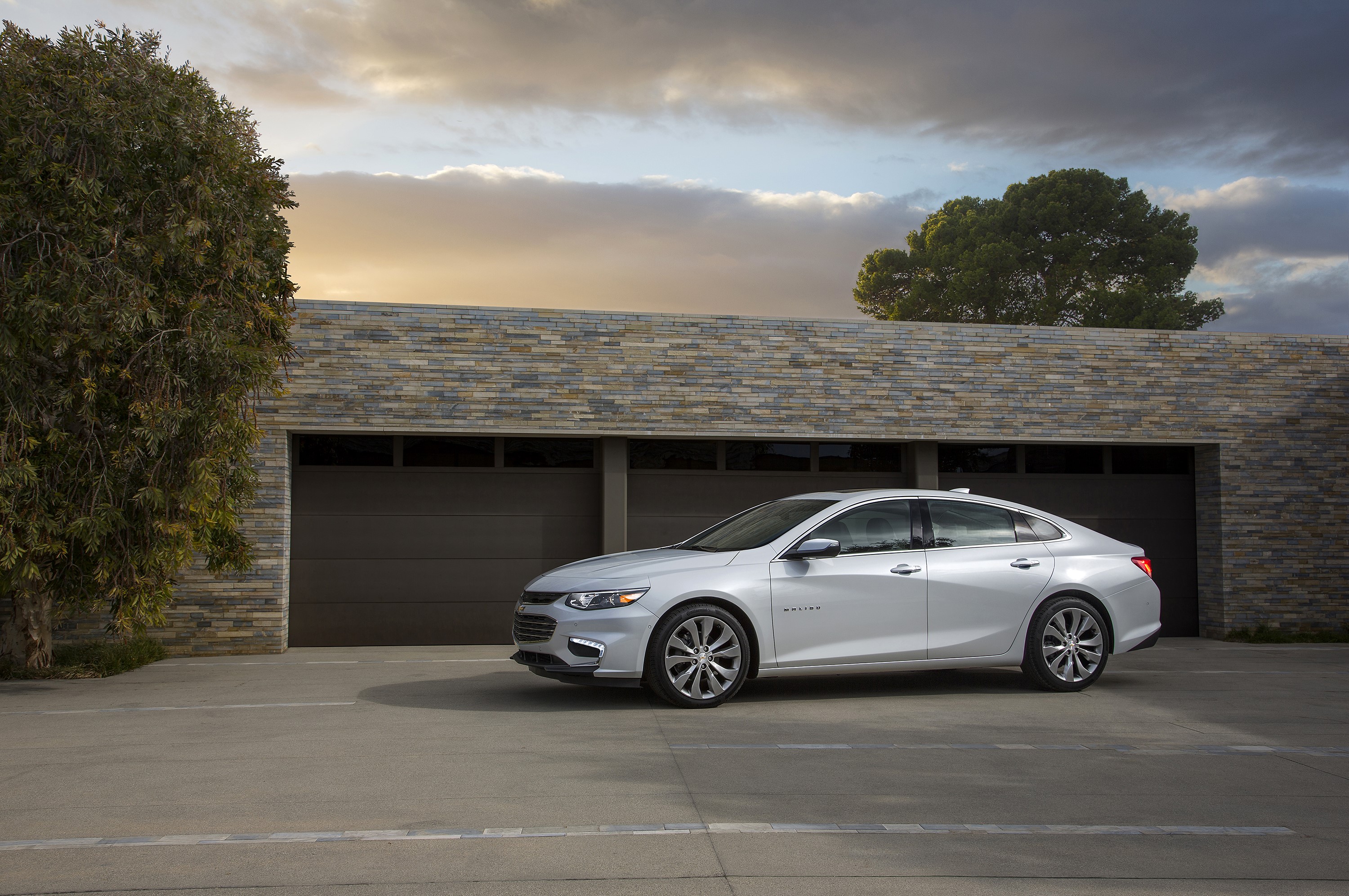 Silver Chevrolet Malibu parked in front of a modern garage HD Wallpaper
