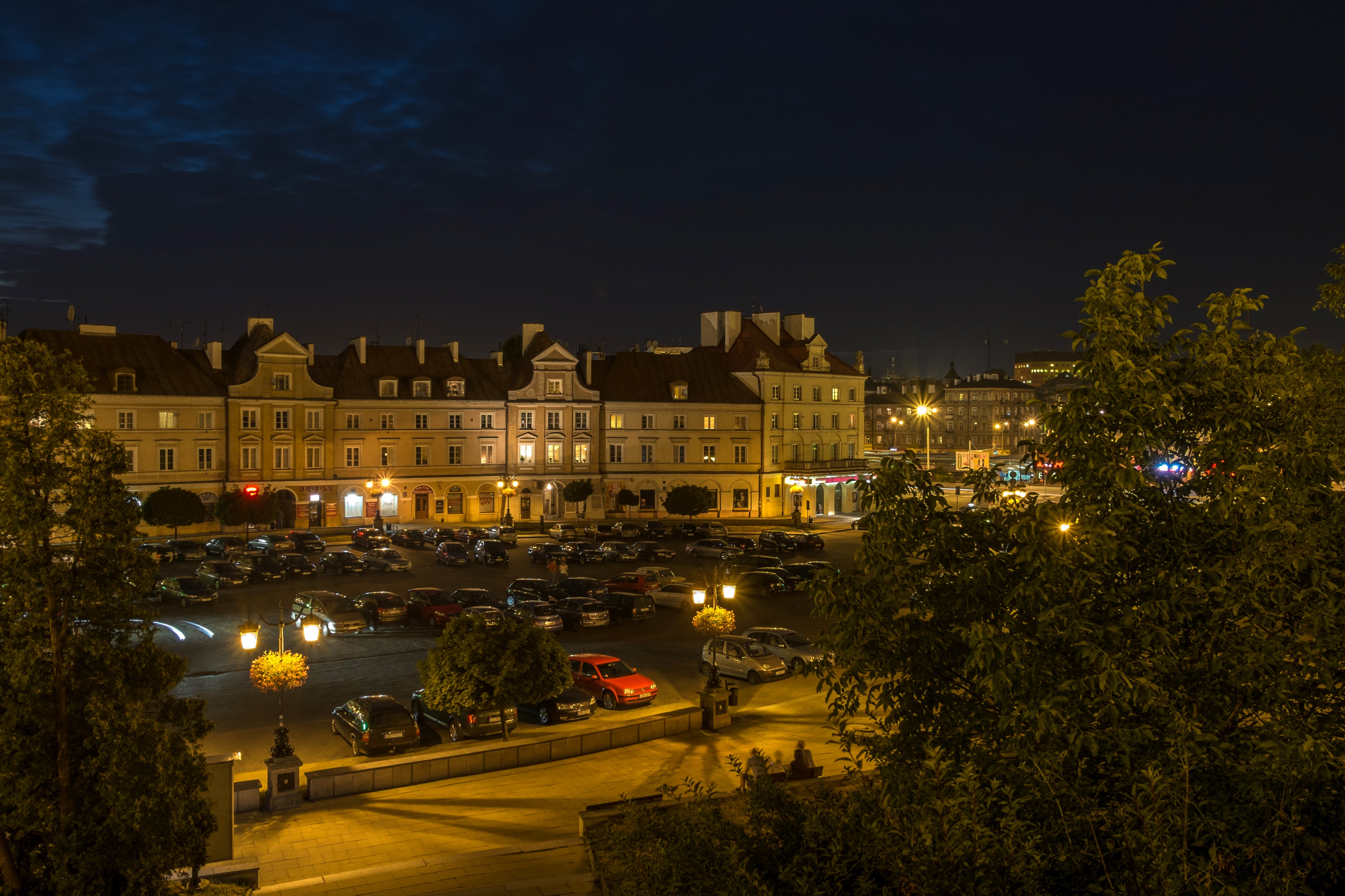 Night view of Lublin, Poland with illuminated buildings and parked cars HD Wallpaper