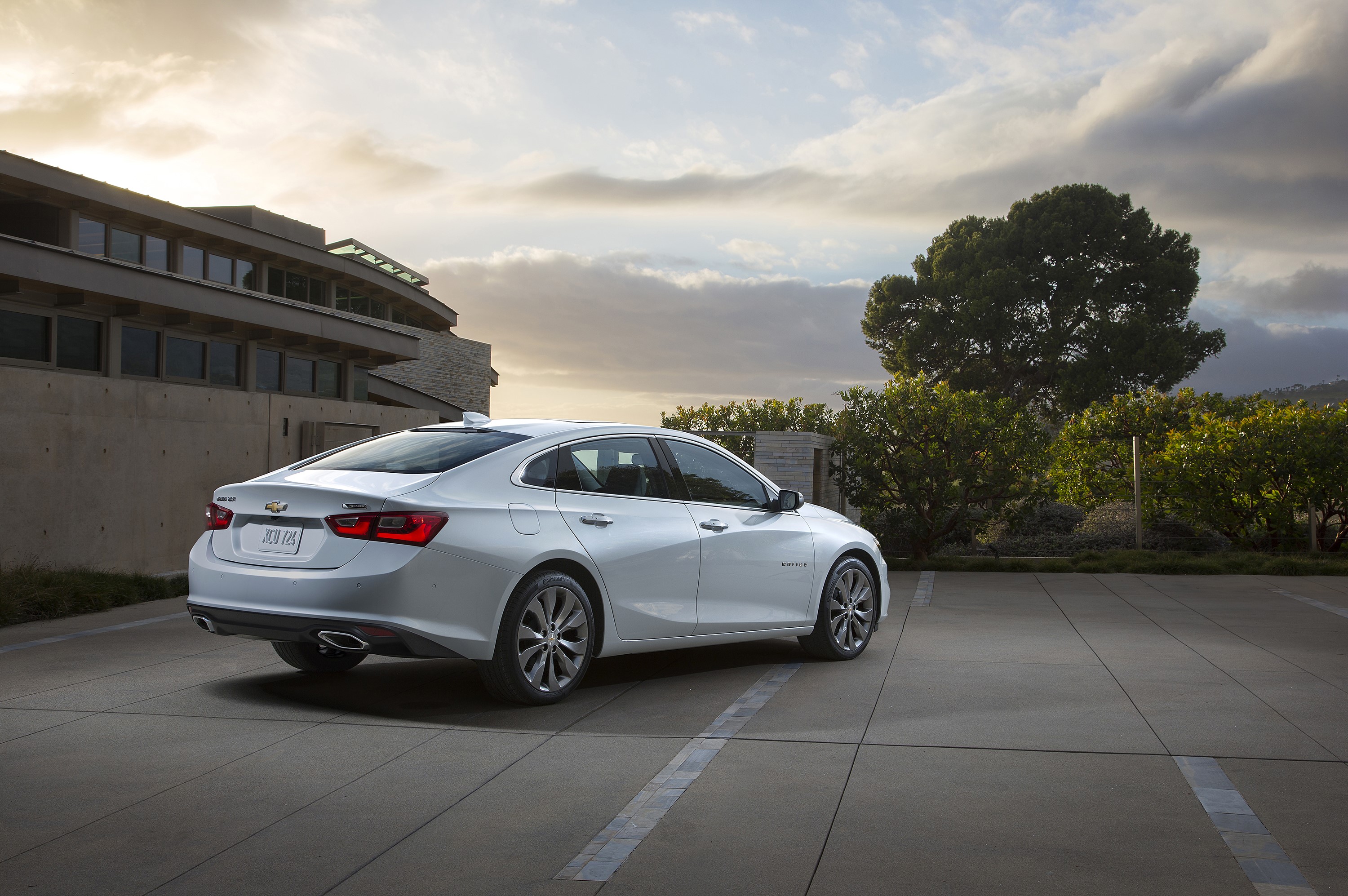 Silver Chevrolet Malibu parked in front of a modern building HD Wallpaper