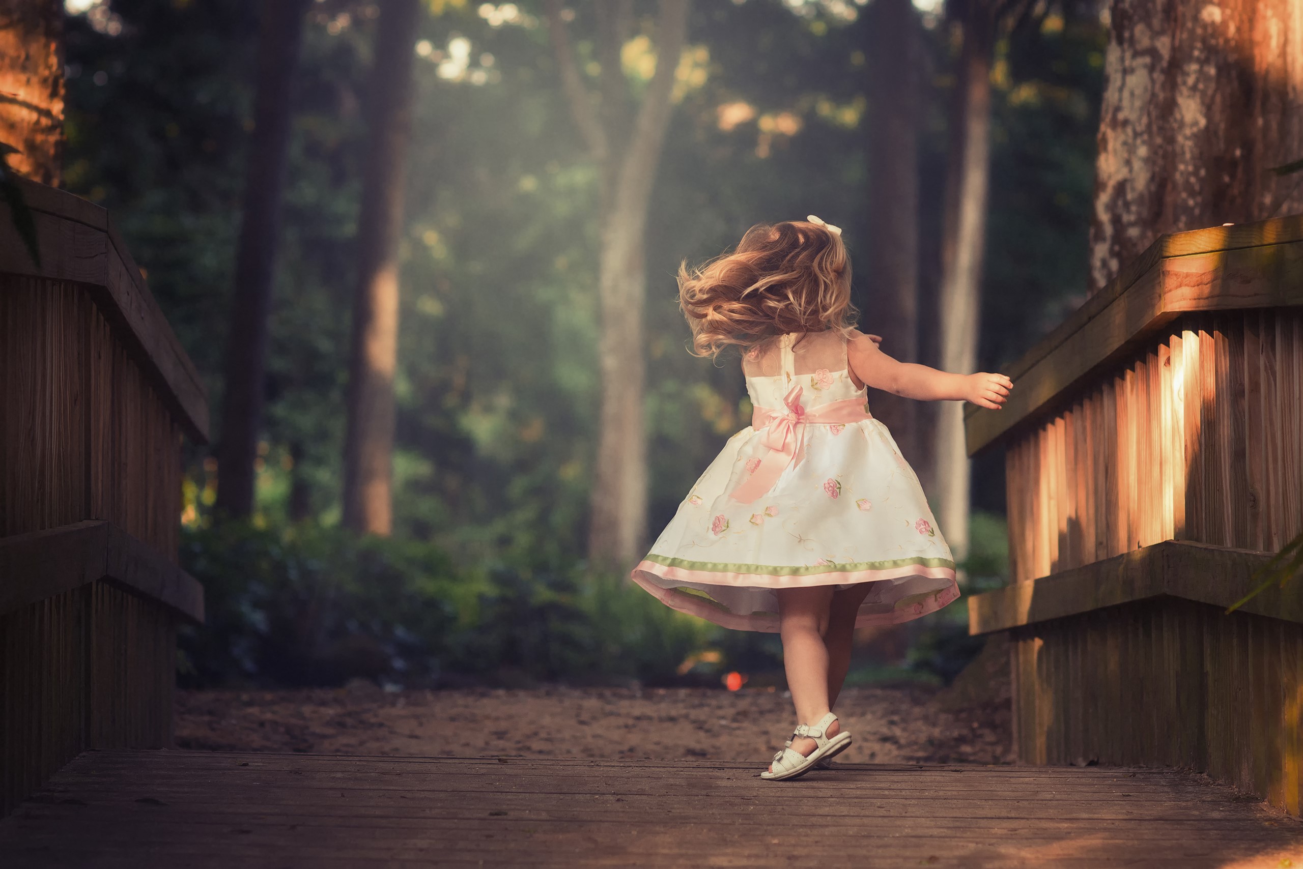 Girl in a dress twirling on a wooden bridge HD Wallpaper