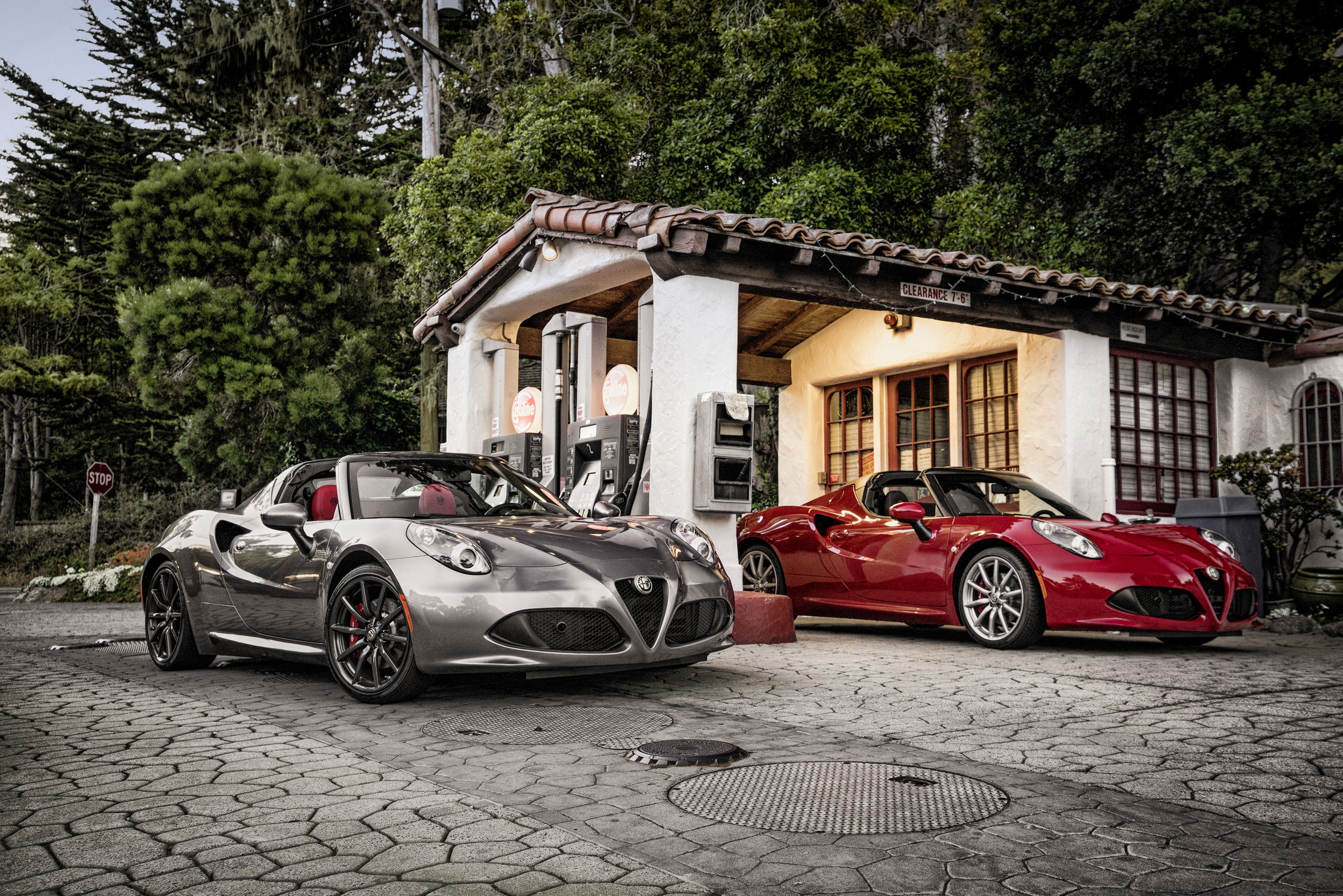 Two Alfa Romeo 4C Spider cars at a vintage gas station HD Wallpaper