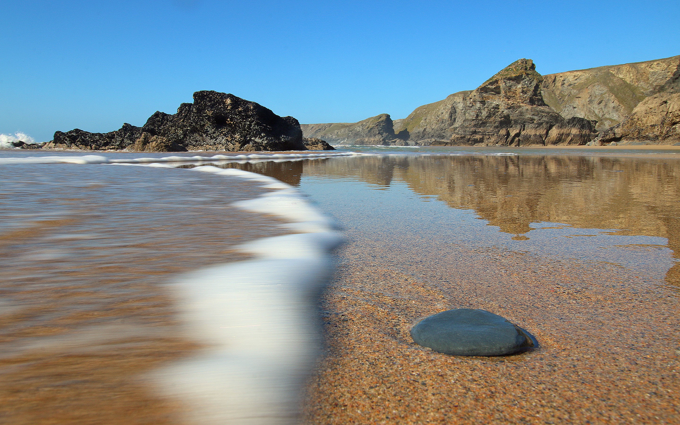 Beach in Cornwall with rocky outcrops and calm sea HD Wallpaper