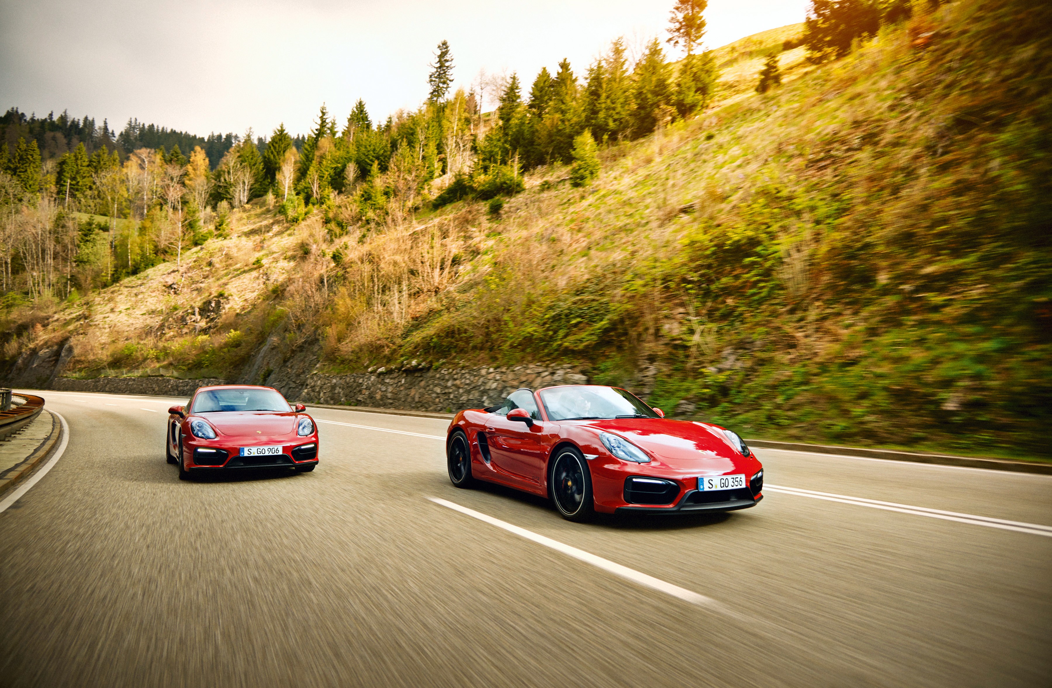 Two red Porsche cars driving on a mountain road HD Wallpaper